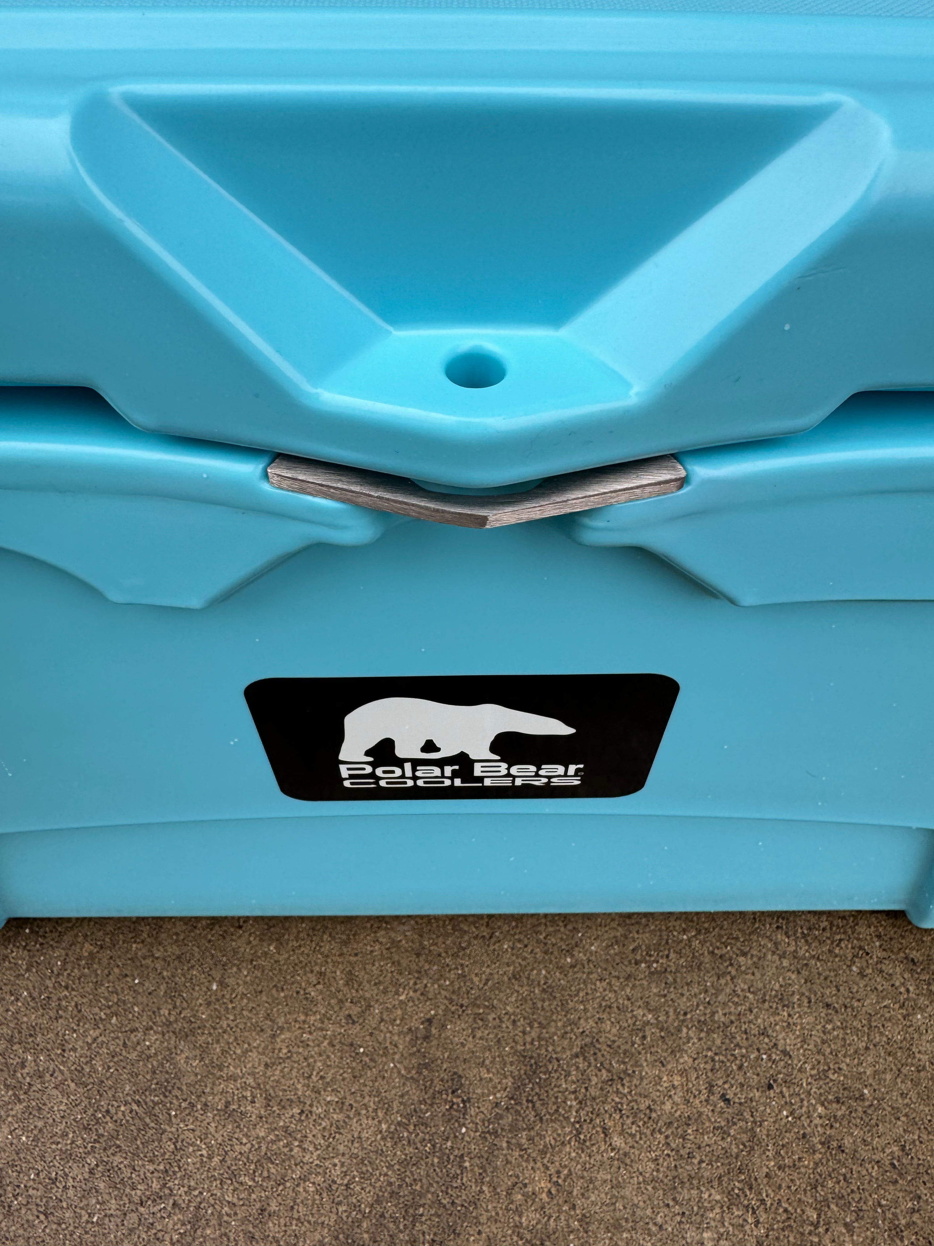Close-up of a blue cooler with a visible brand logo on a carpeted floor.