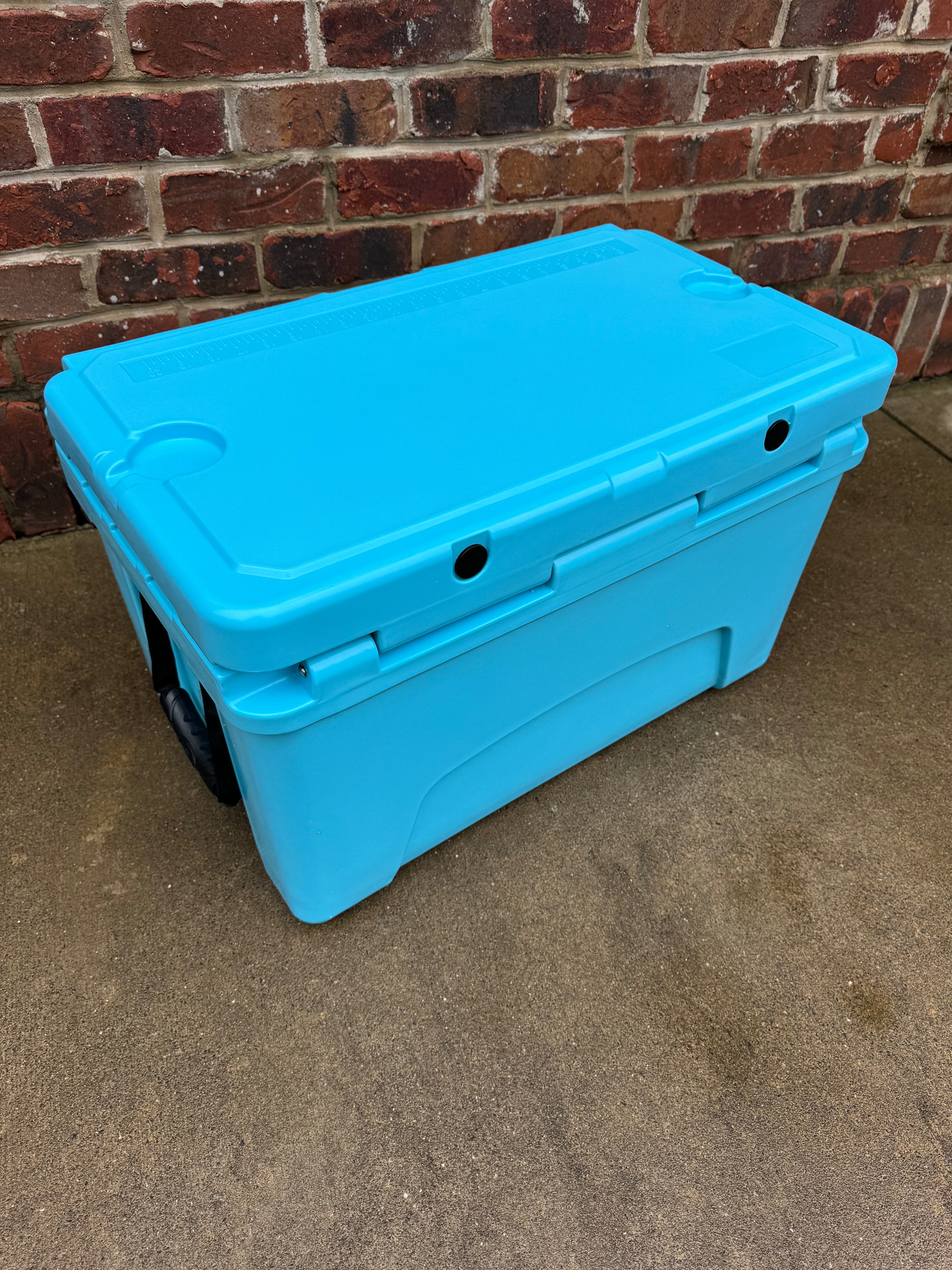 Blue cooler box on a concrete surface with a brick wall background