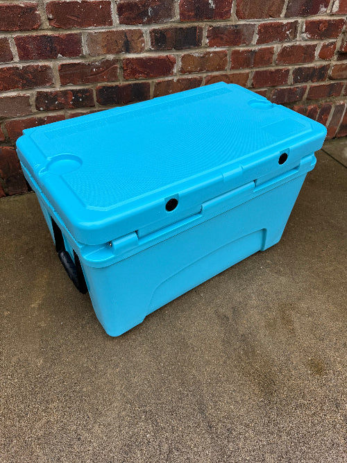 Blue cooler box on a concrete surface with a brick wall background
