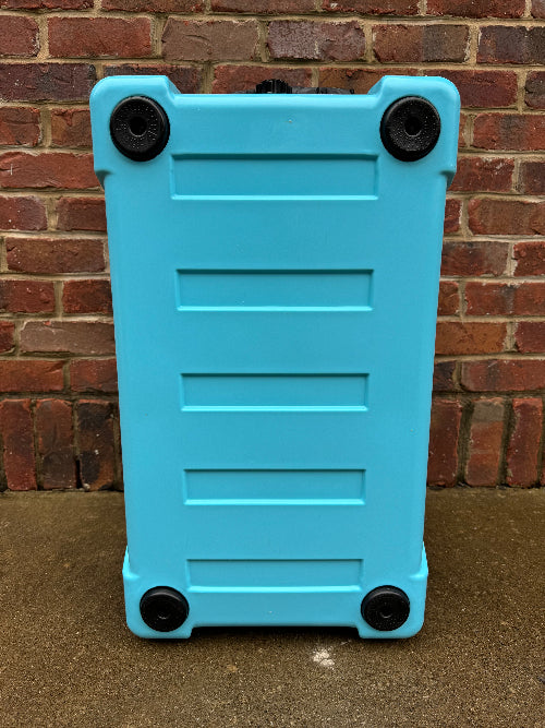 Blue suitcase with black wheels against a brick wall.