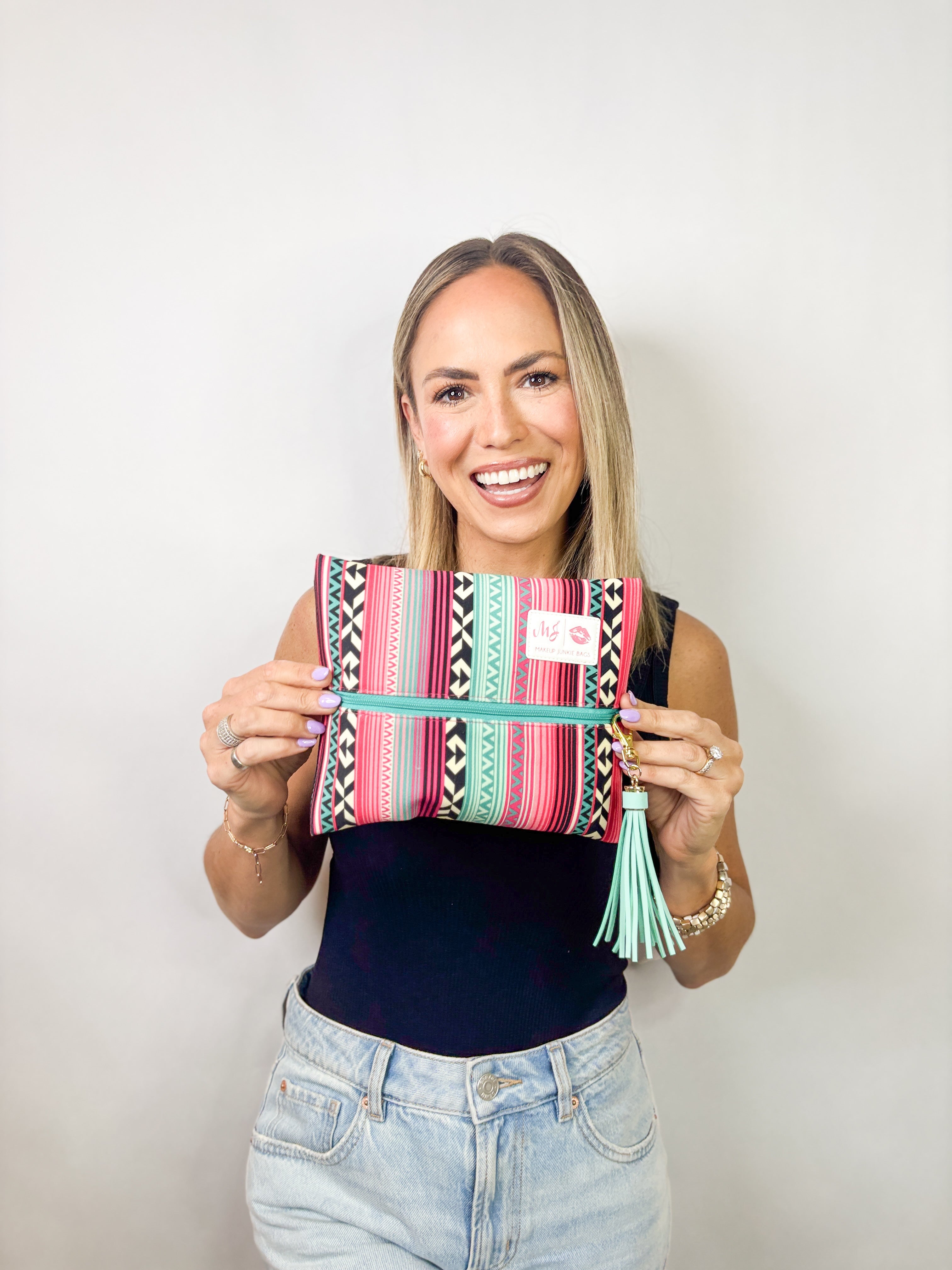 Woman holding a colorful striped bag with a tassel against a white background