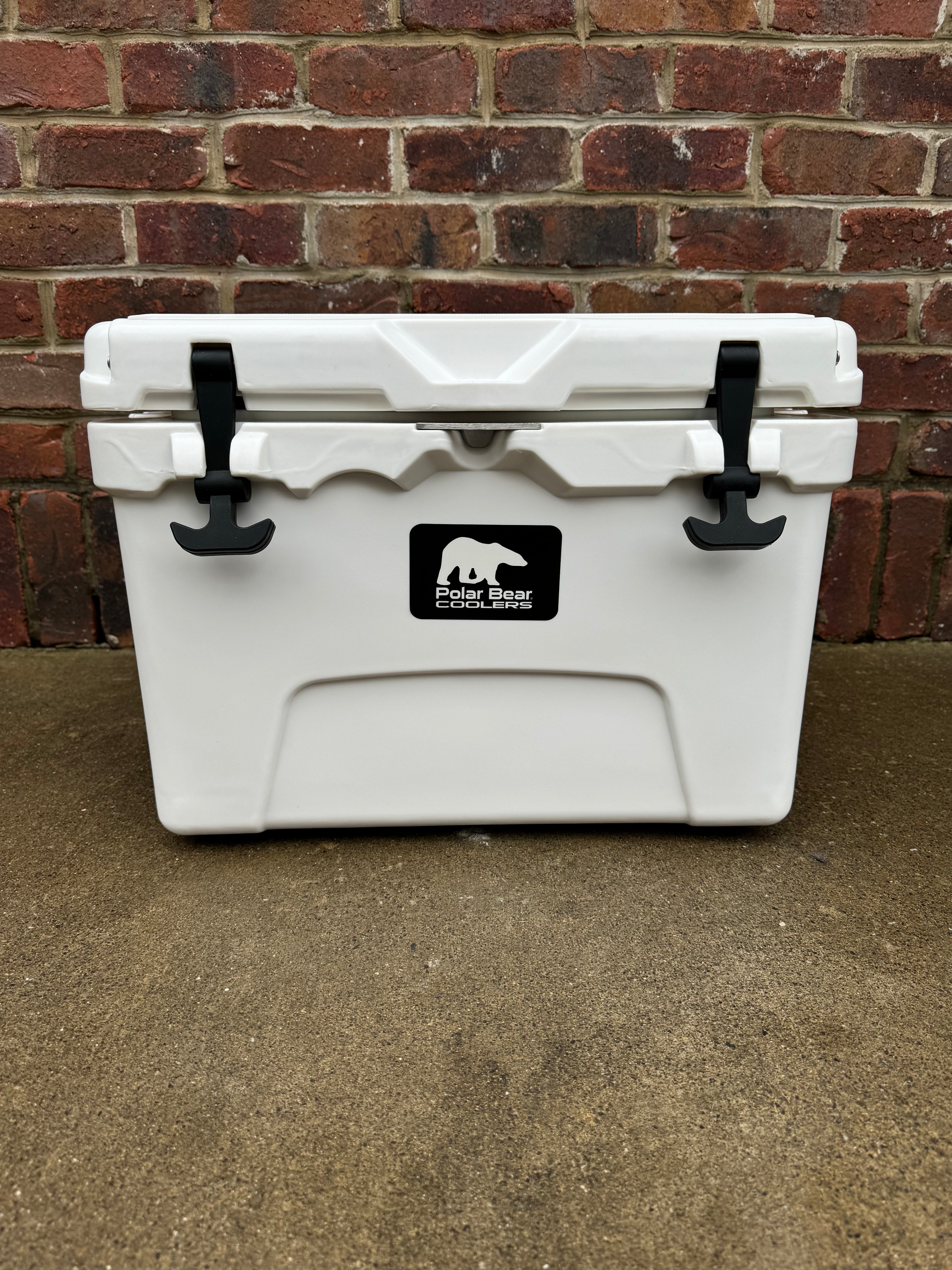 White cooler with a logo on it, placed against a brick wall.