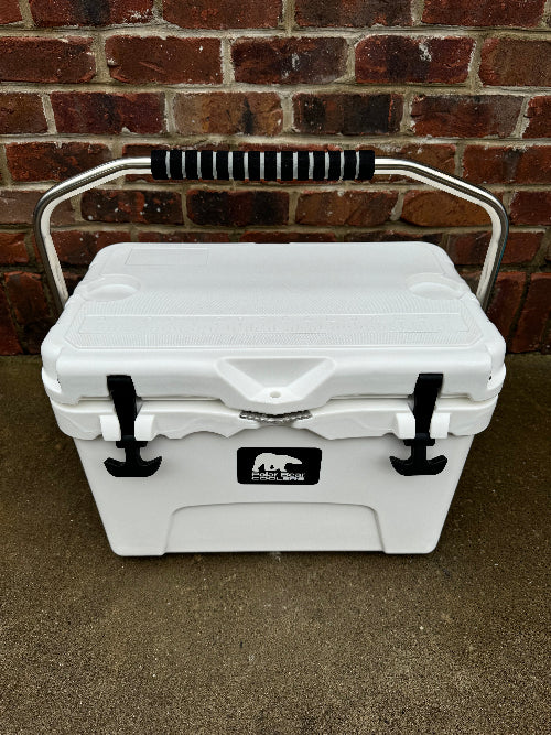 White cooler box with black handles and a logo on a brick wall background