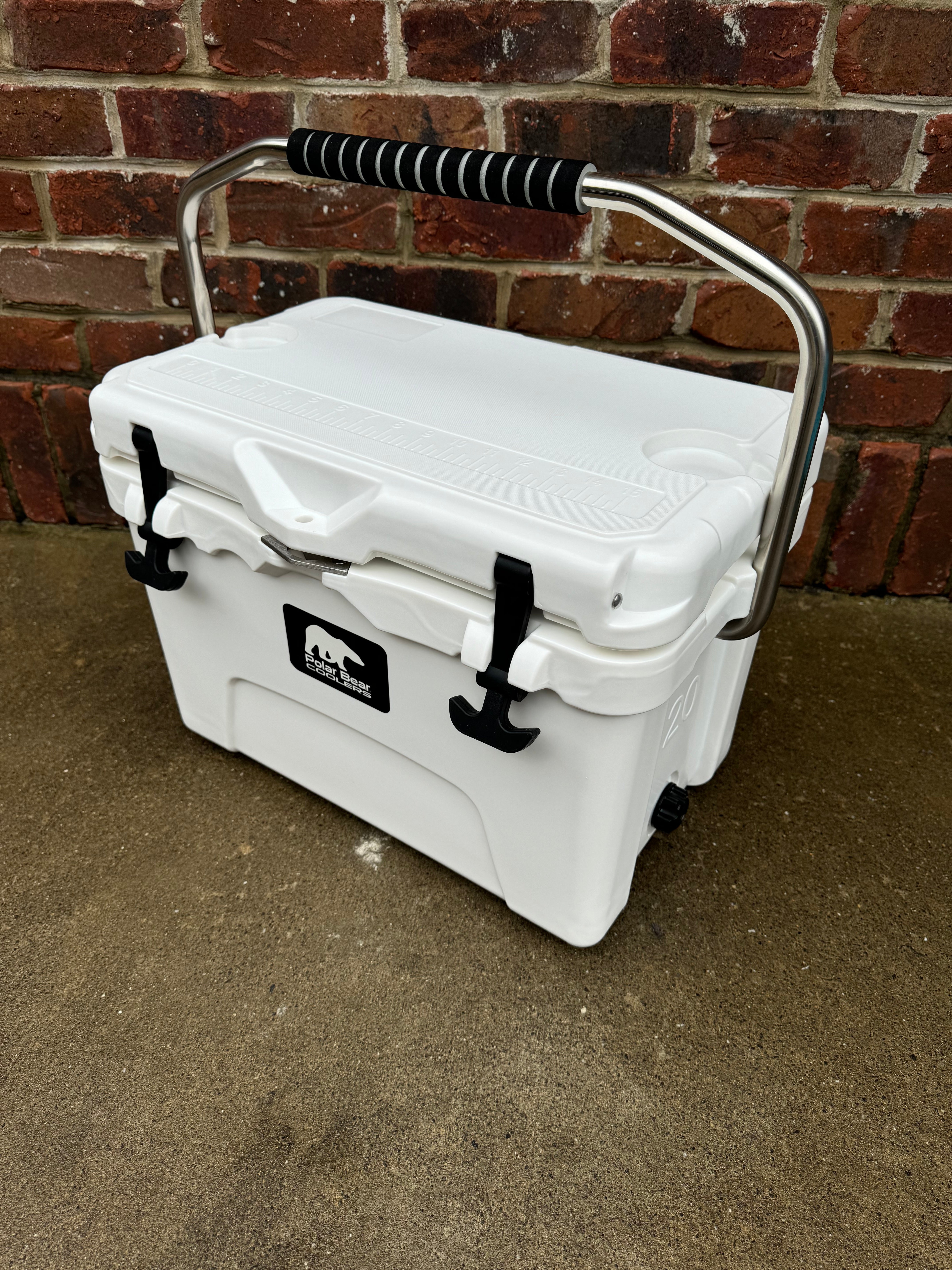 White cooler with a handle against a brick wall.