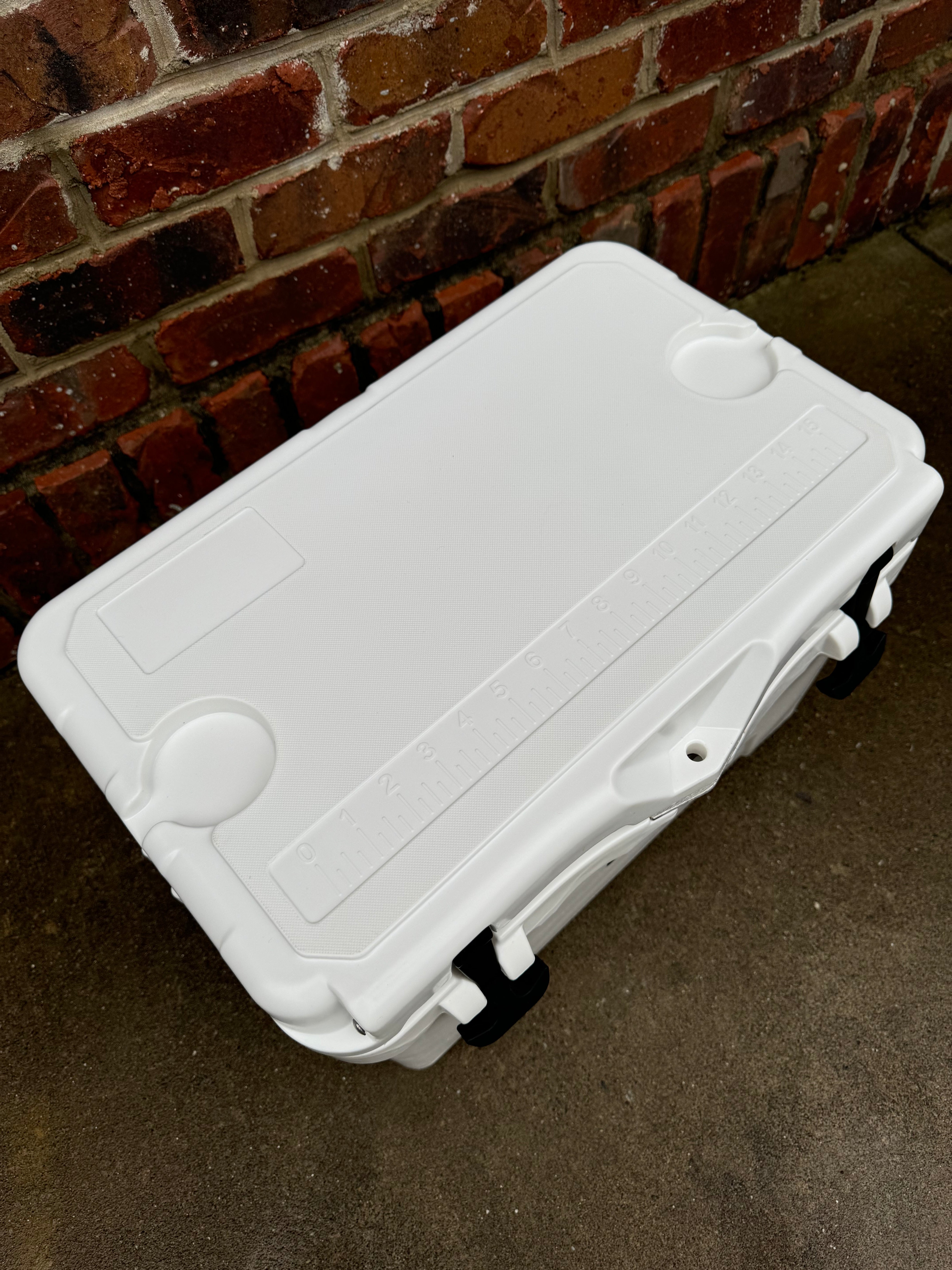 White cooler box on a concrete surface with a brick wall background