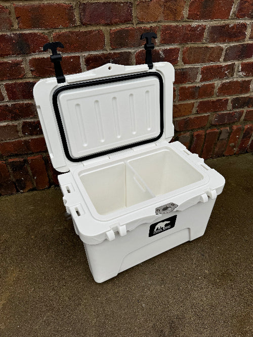 White cooler box with open lid against a brick wall.