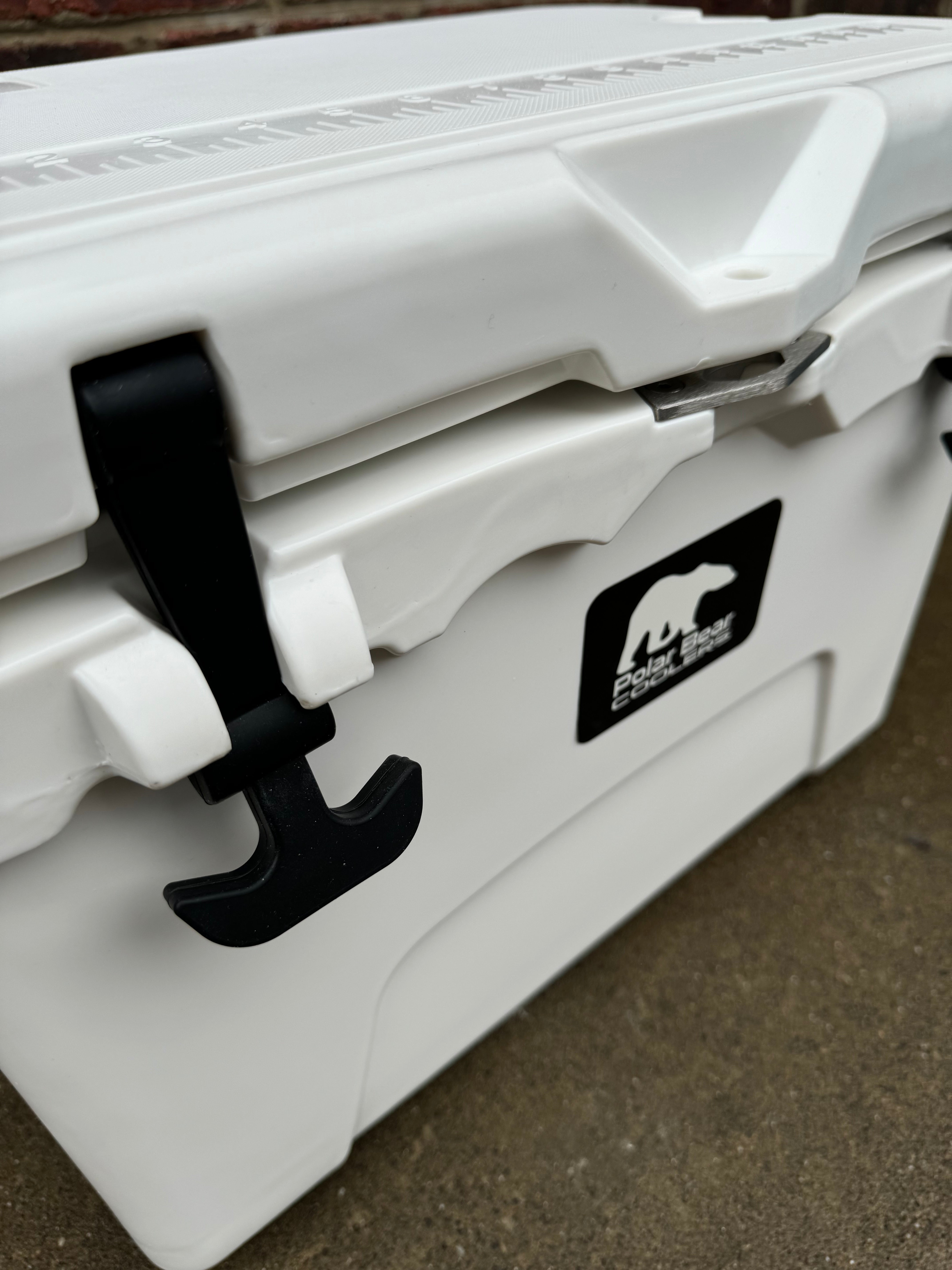 White cooler with black handle and bear logo on a brown surface