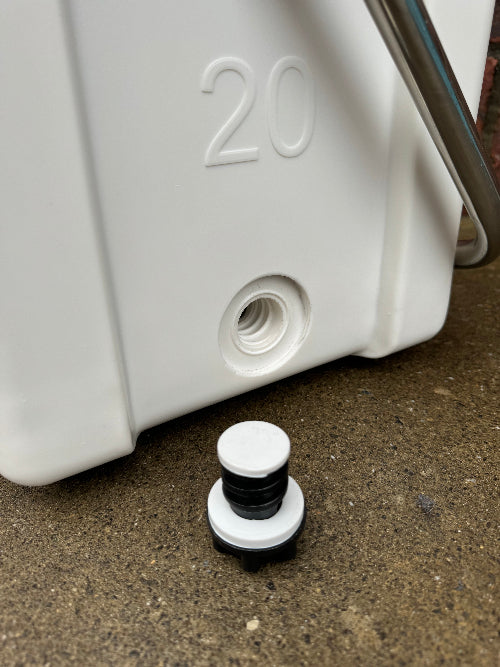 White plastic component with a black and white cap on a concrete surface
