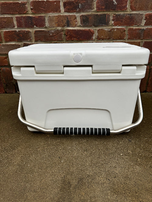 White cooler with a black handle against a brick wall.