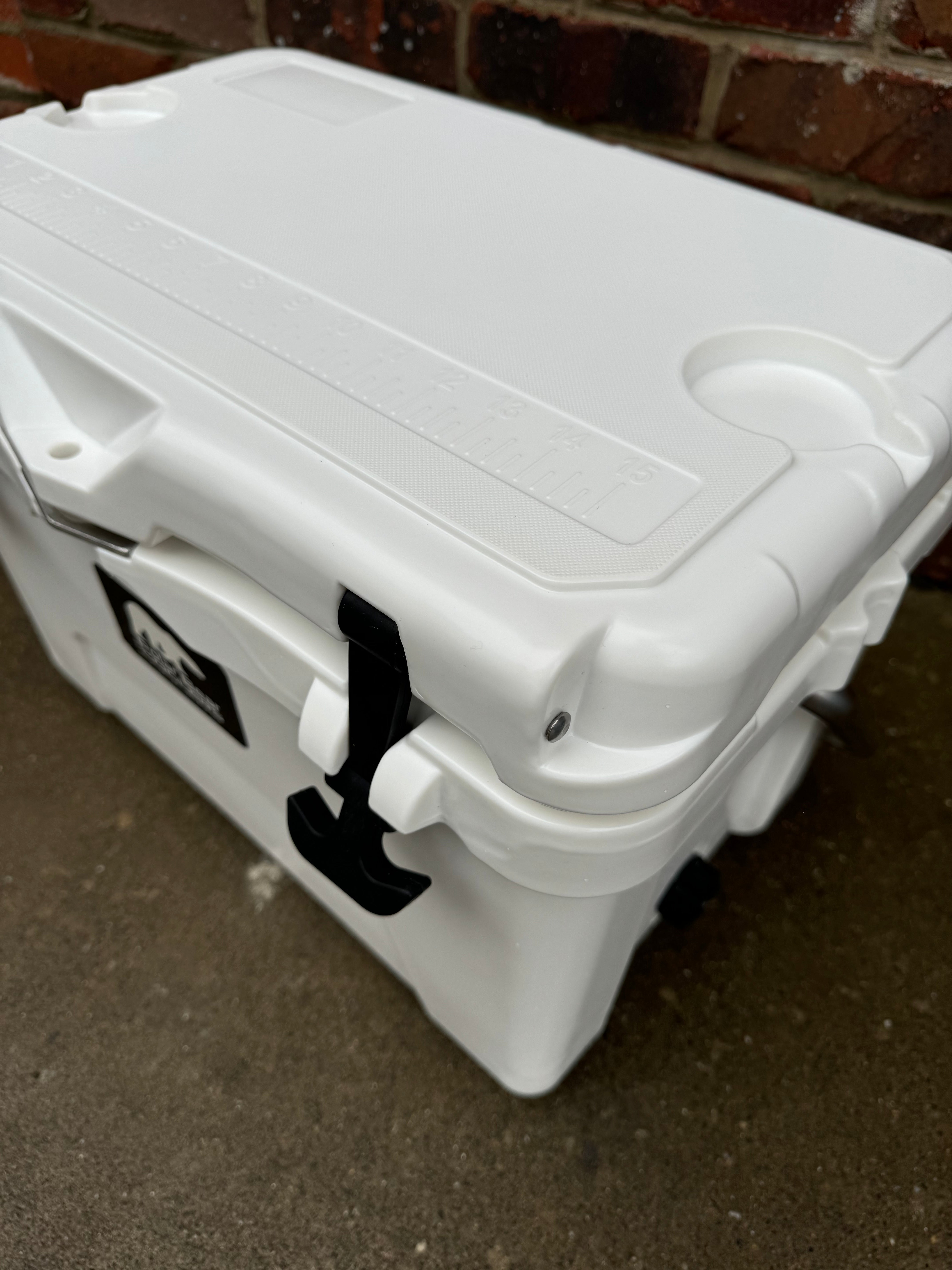 White cooler box with a black handle on a concrete surface.