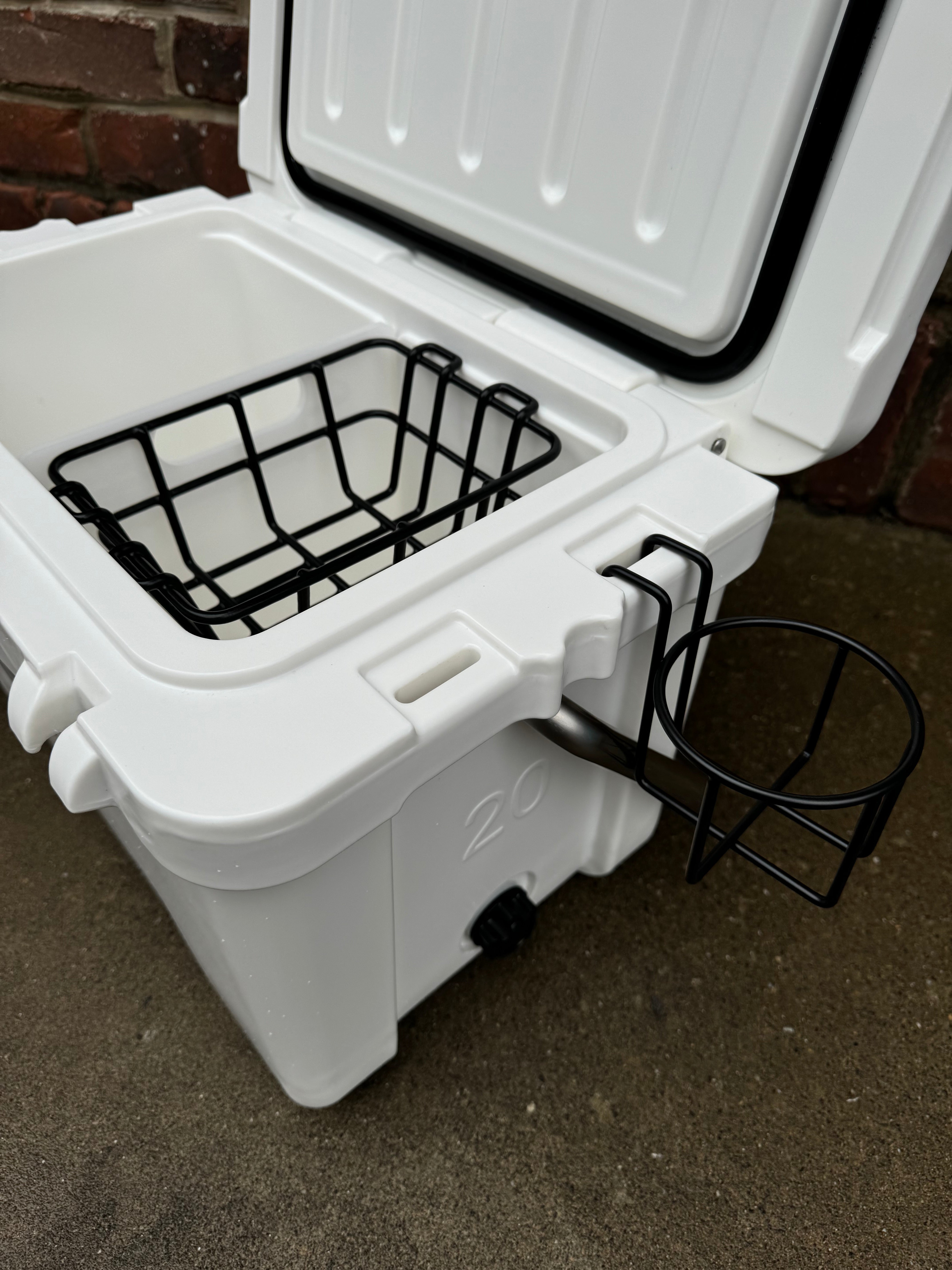 White cooler with black wire basket on a concrete surface.