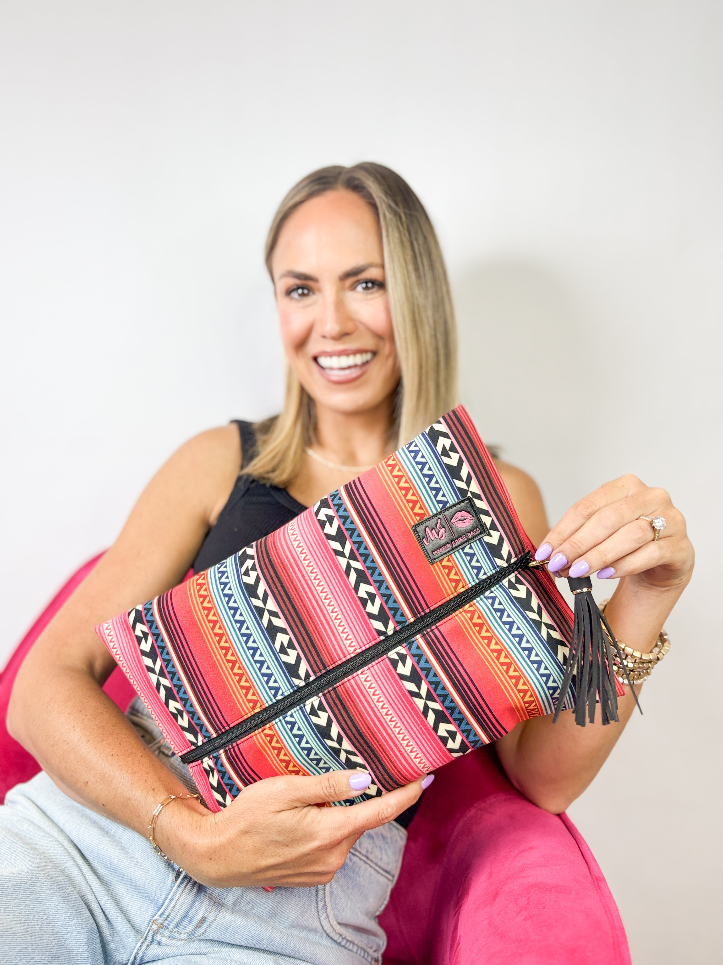 Woman holding a colorful patterned clutch bag against a plain background