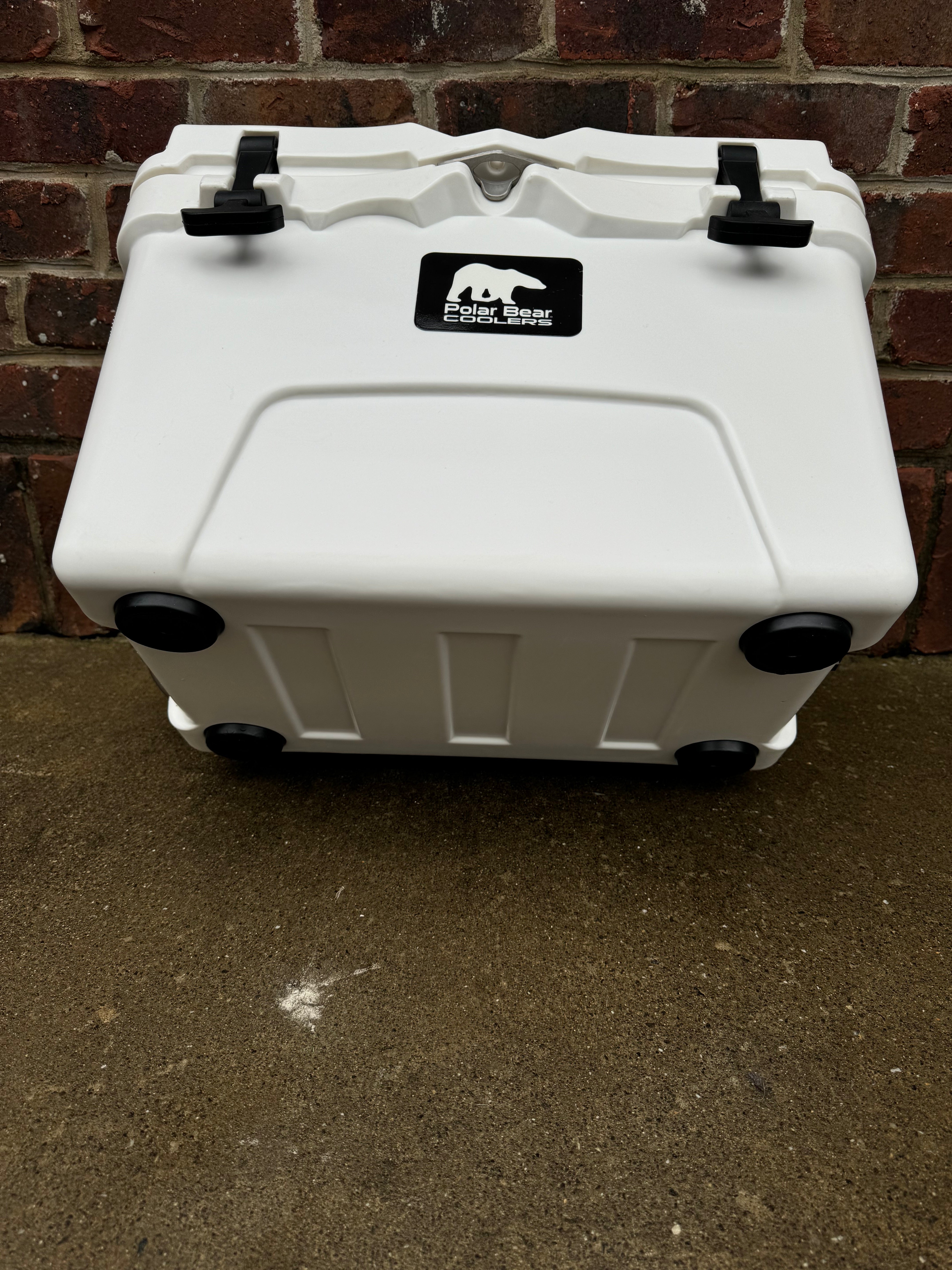White cooler with a logo on a concrete surface and brick wall background
