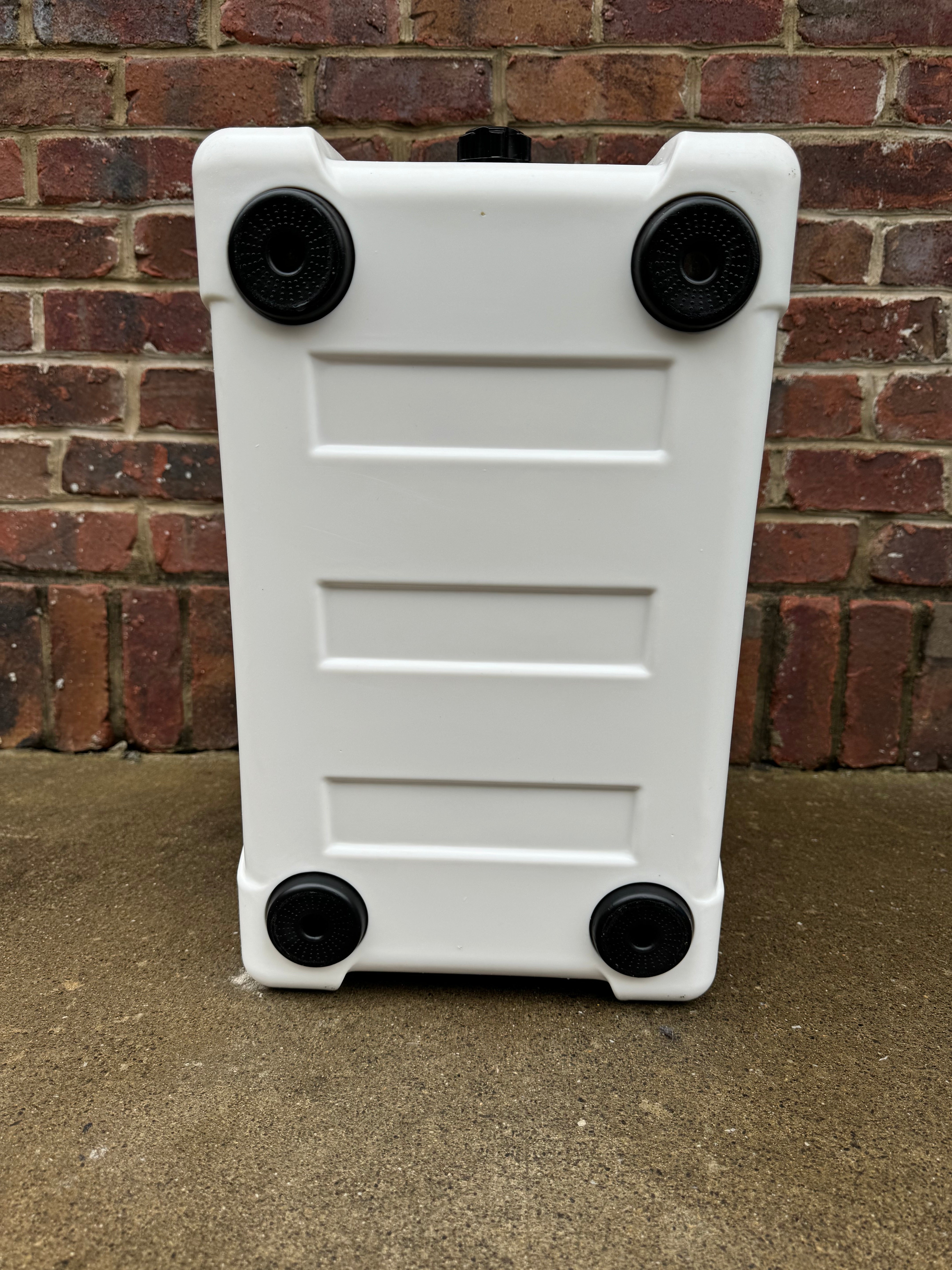 White plastic step stool with black wheels against a brick wall.