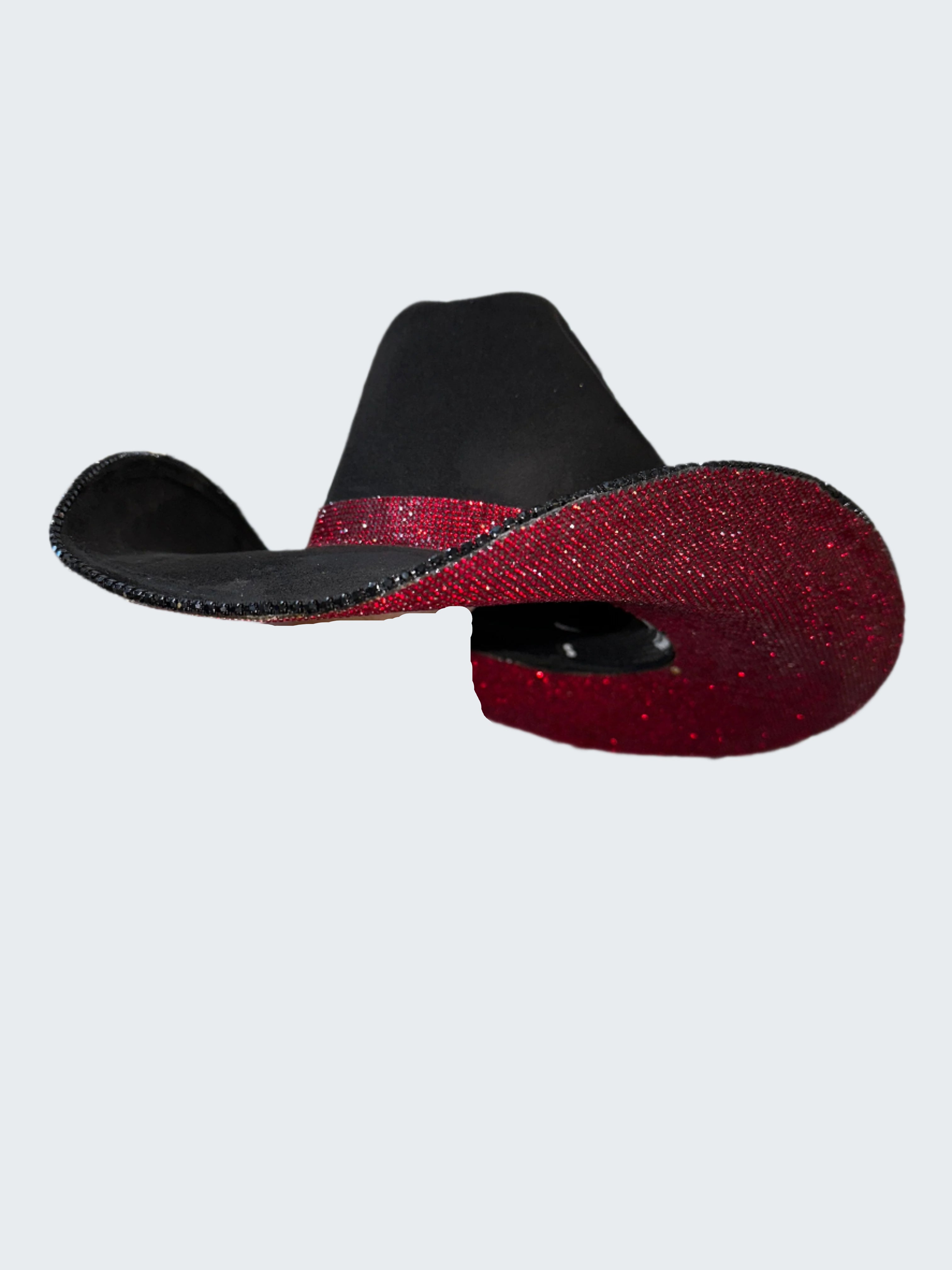 Black and red glittery cowboy hat held by a hand against a sequin background