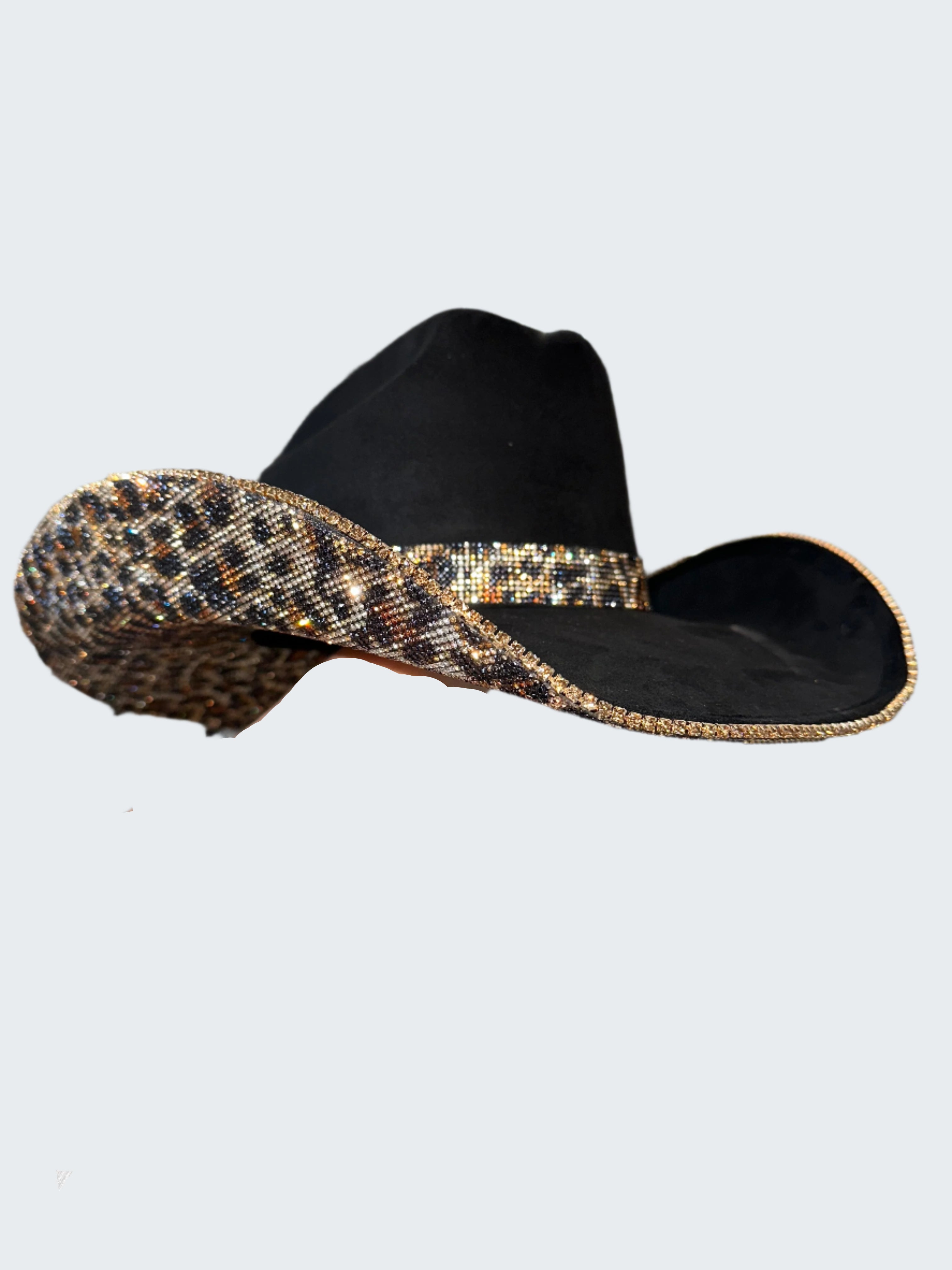 Black sandal with gold sequins held by a hand against a sparkling background
