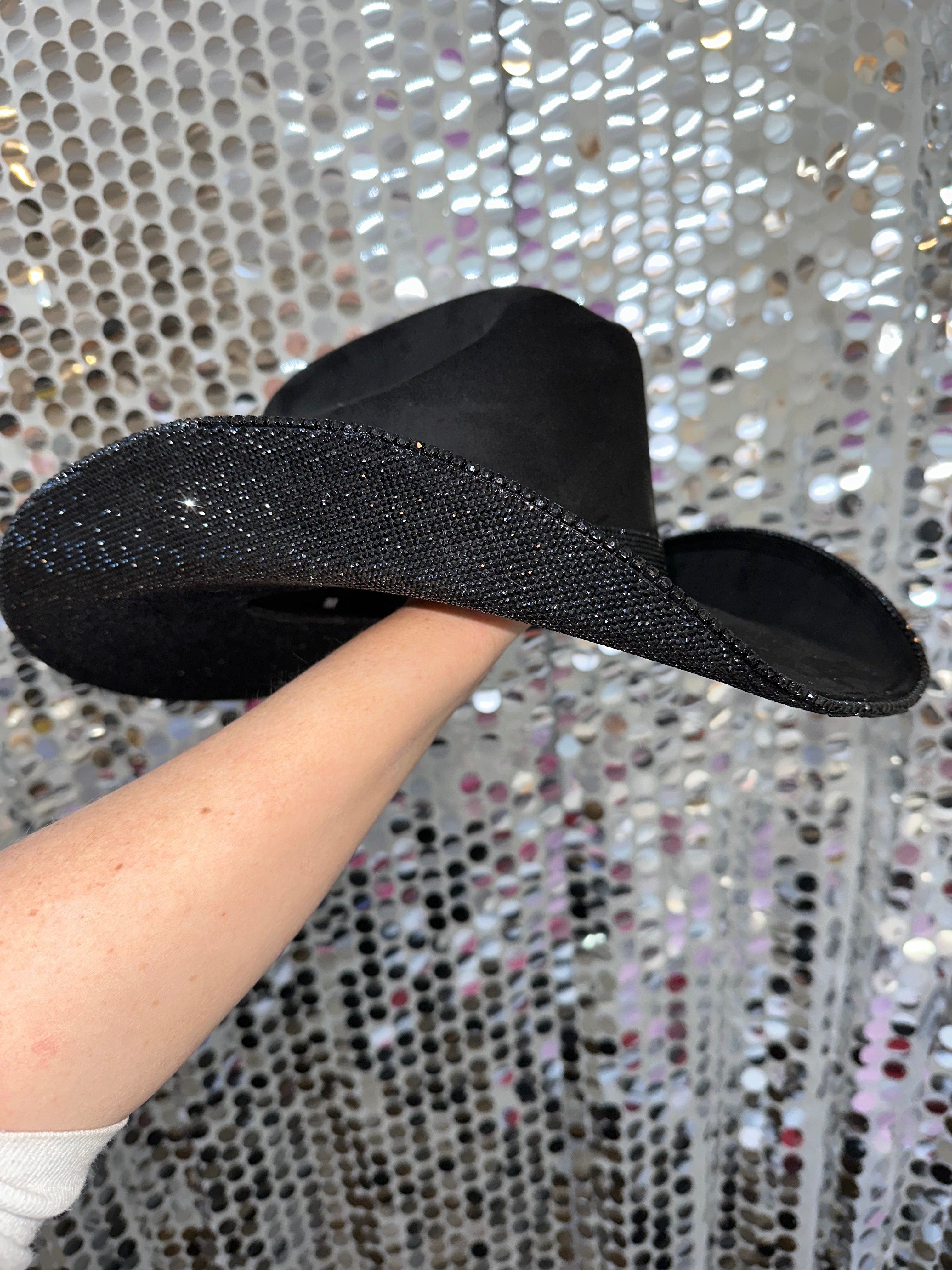 Black glittery shoe insole held by a hand against a silver sequin background