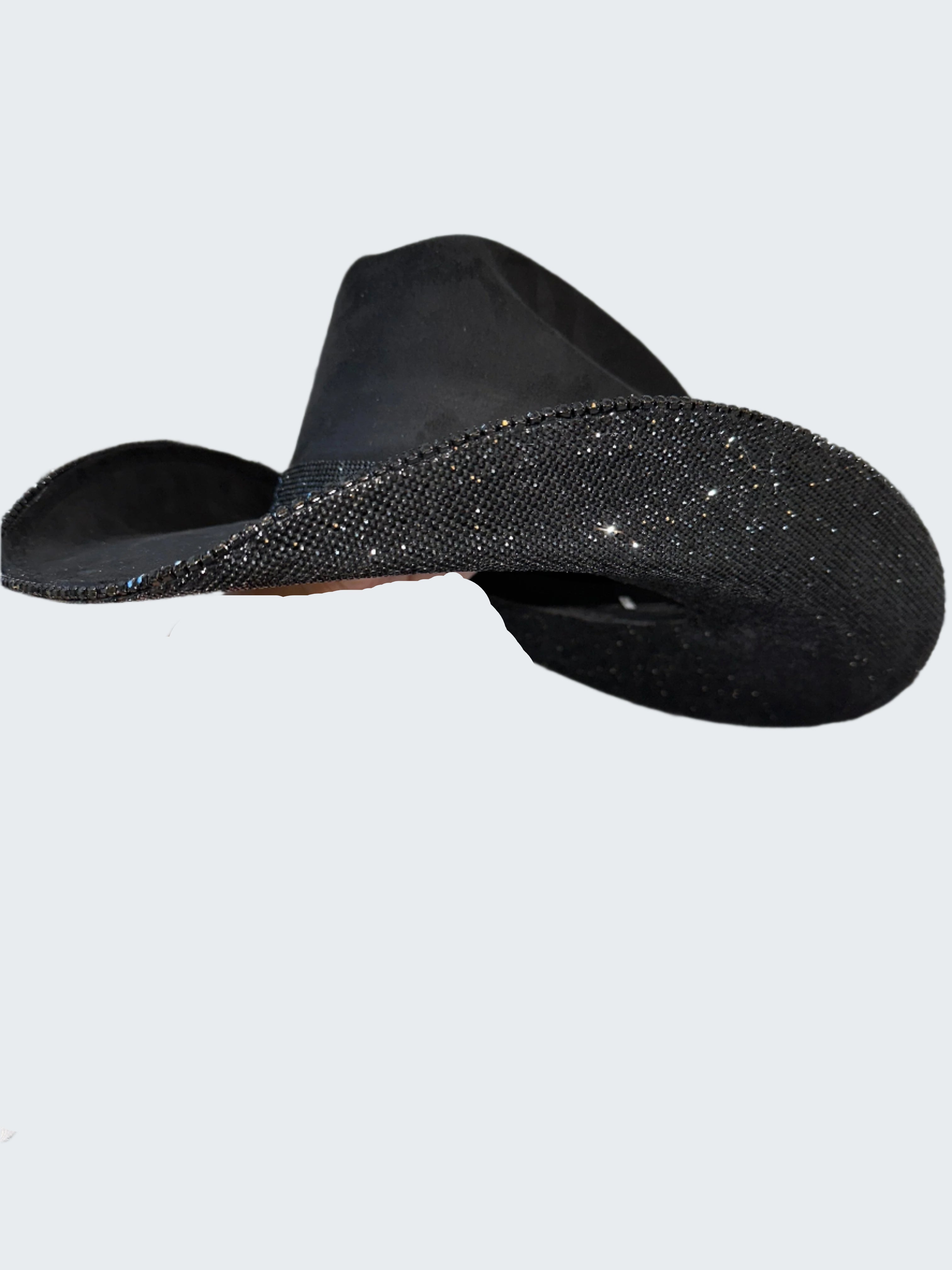 Black flat sandal with glittery sole held against a sparkling background