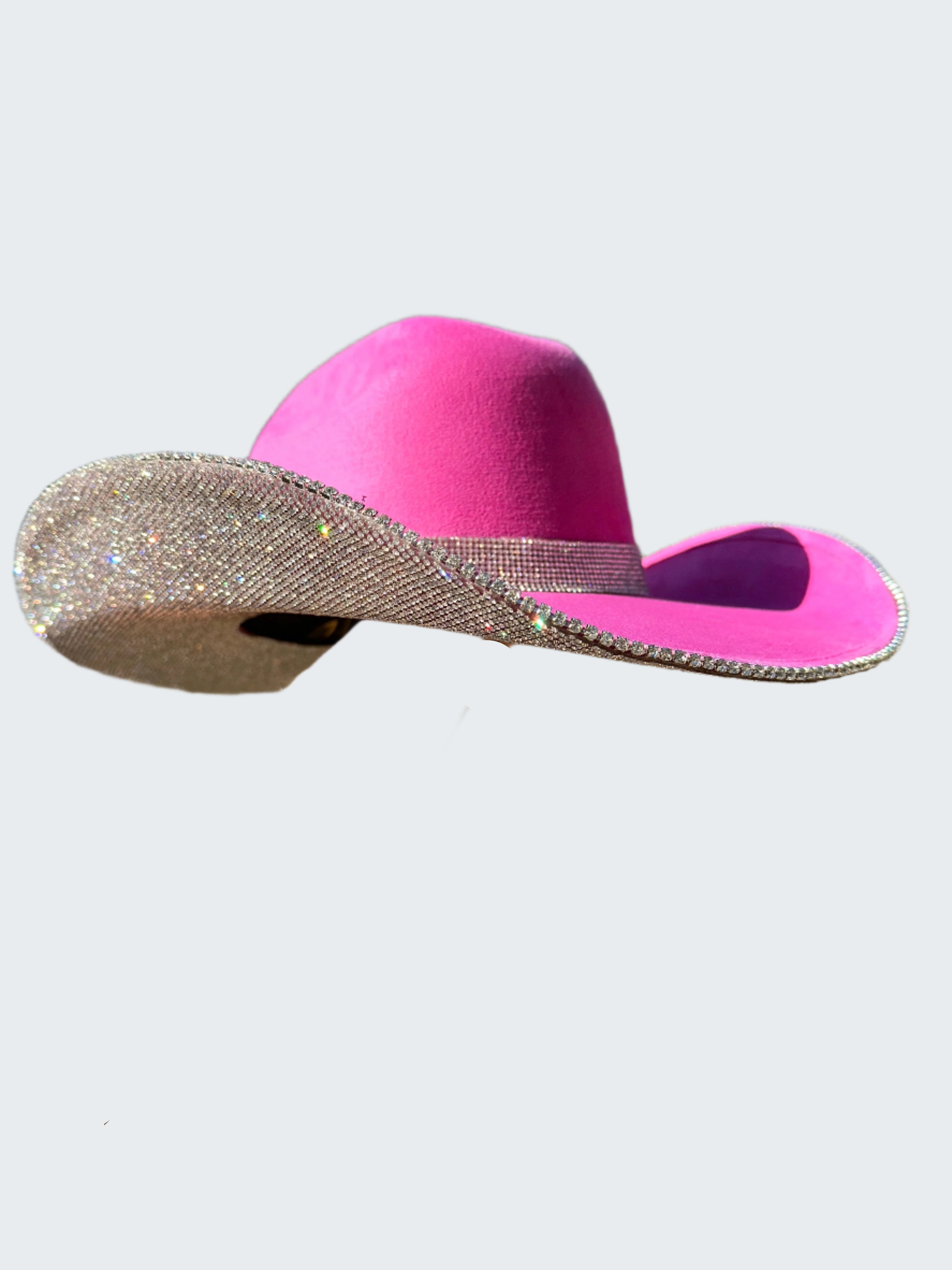 Pink cowboy hat with a silver band held by a person outdoors.