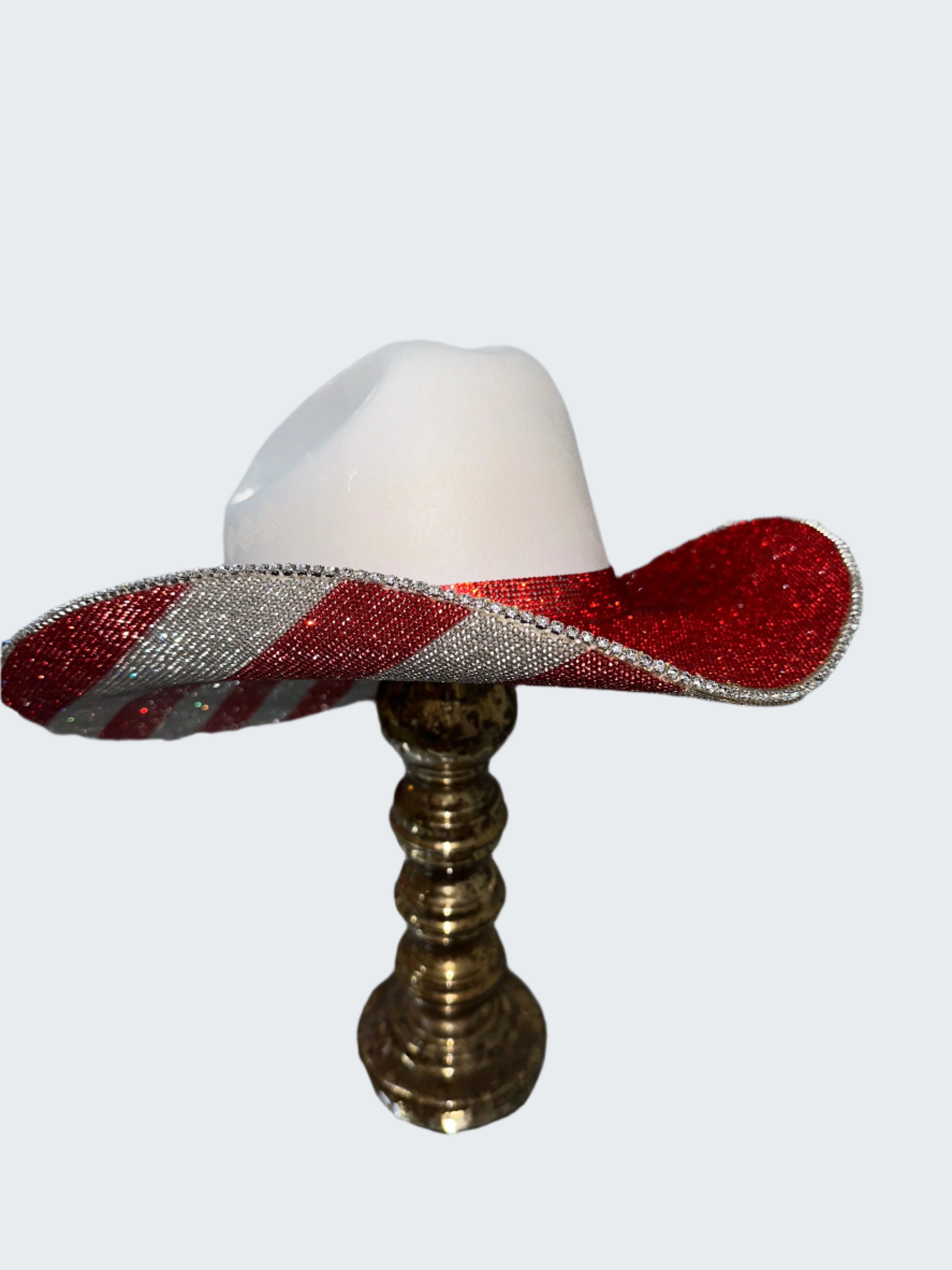 Small white lamp with a red and silver striped shade on a gold stand against a glittery background