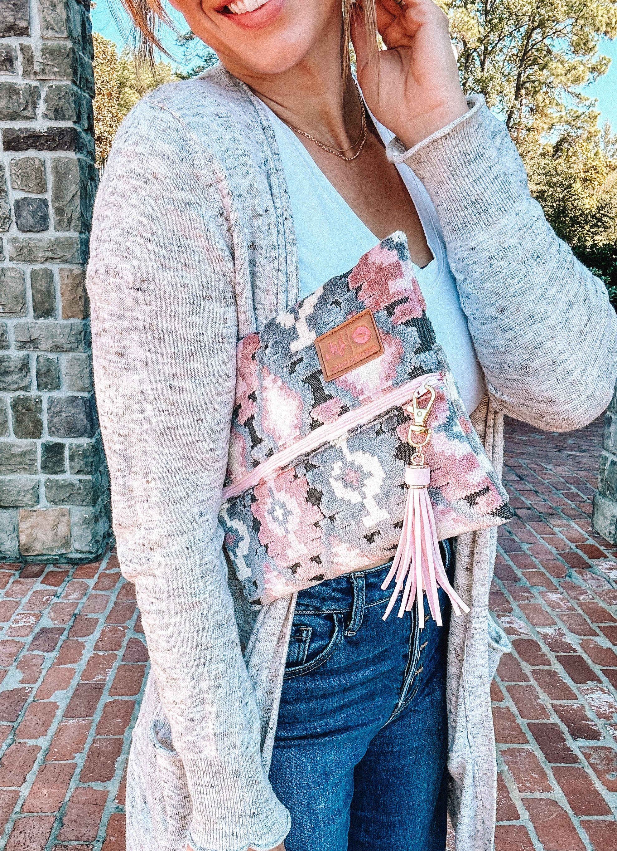 Woman holding a floral handbag with a brick wall and trees in the background
