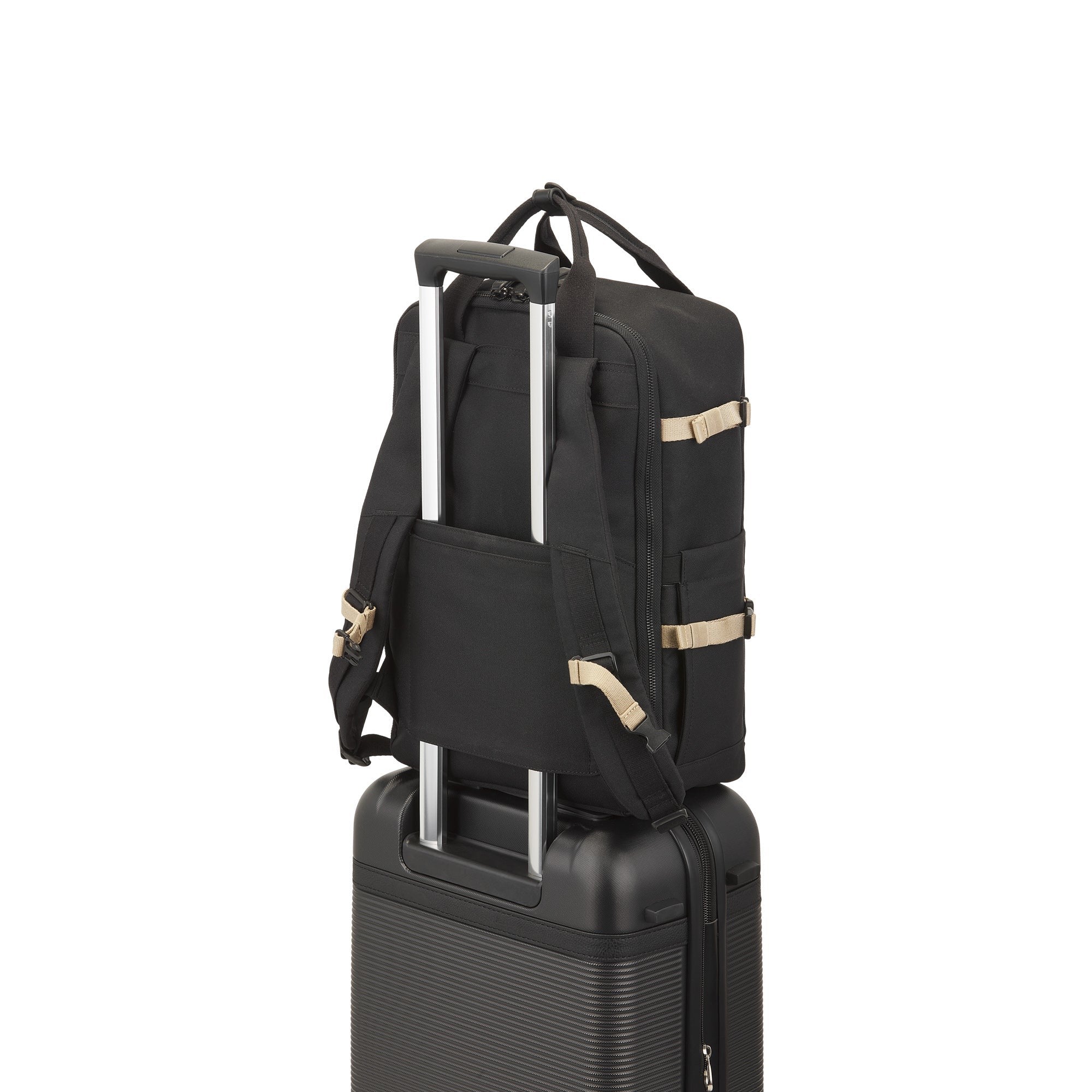 Black backpack on top of a black suitcase with gold accents on a white background