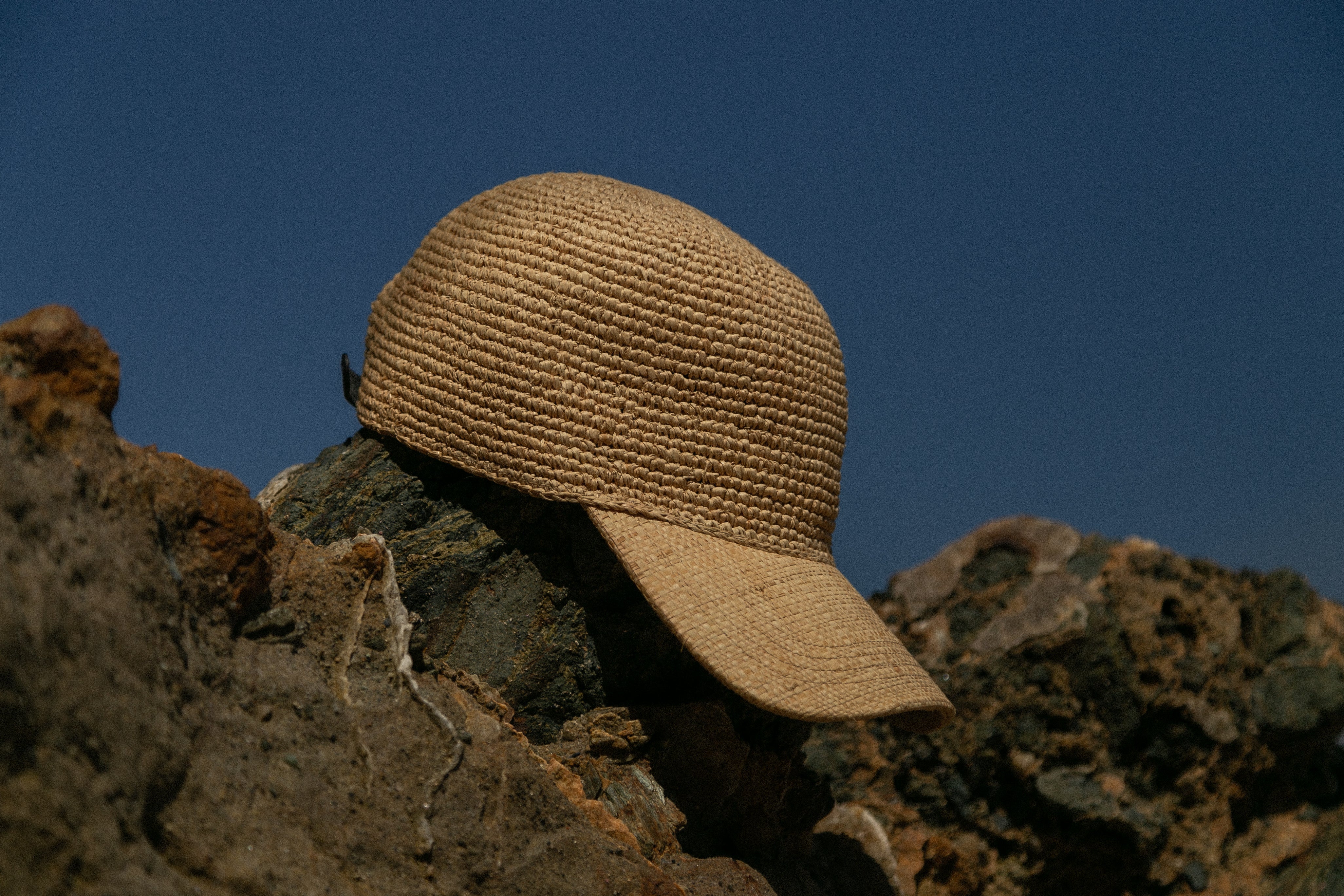 Brown straw hat on a rocky surface with a clear blue sky