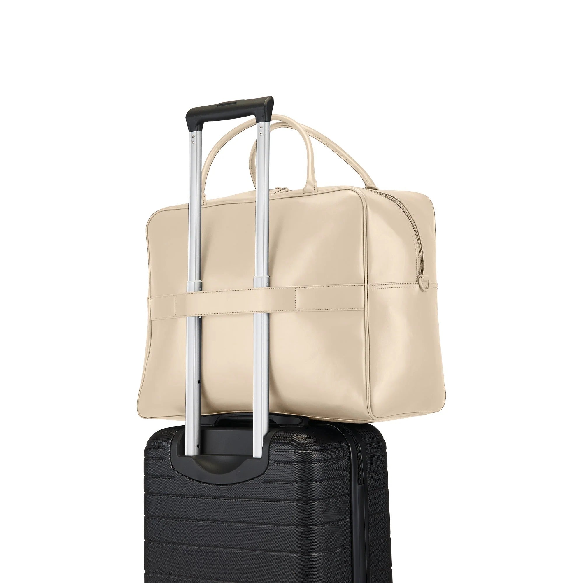 Beige travel bag with handle on top of a black suitcase on a white background