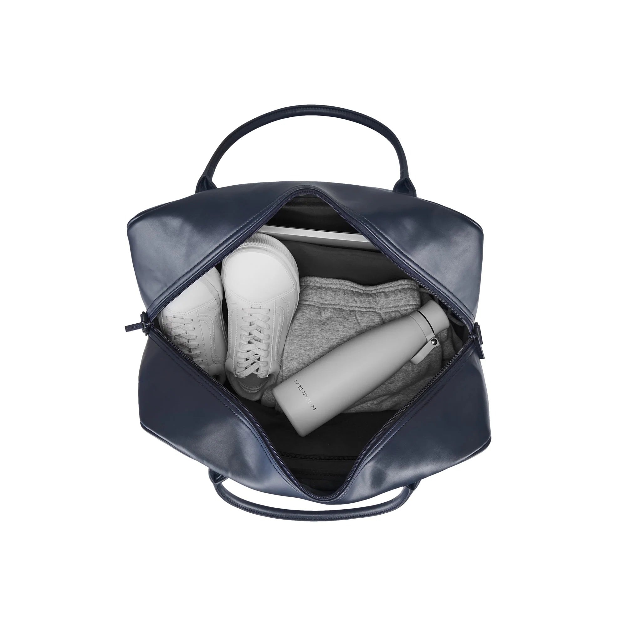 Navy blue backpack with a white sneaker, gray sweatshirt, and white bottle inside on a white background