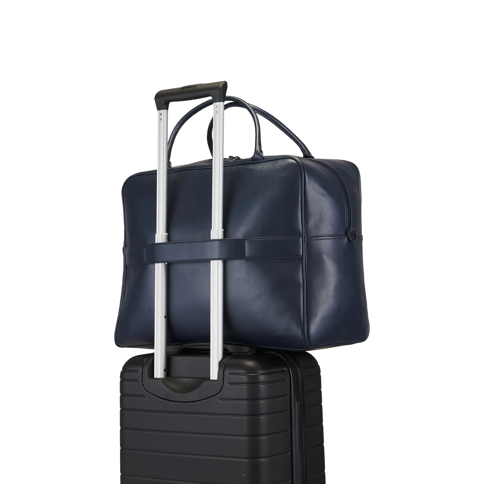 Navy leather duffel bag with silver handle on top of a black suitcase on a white background