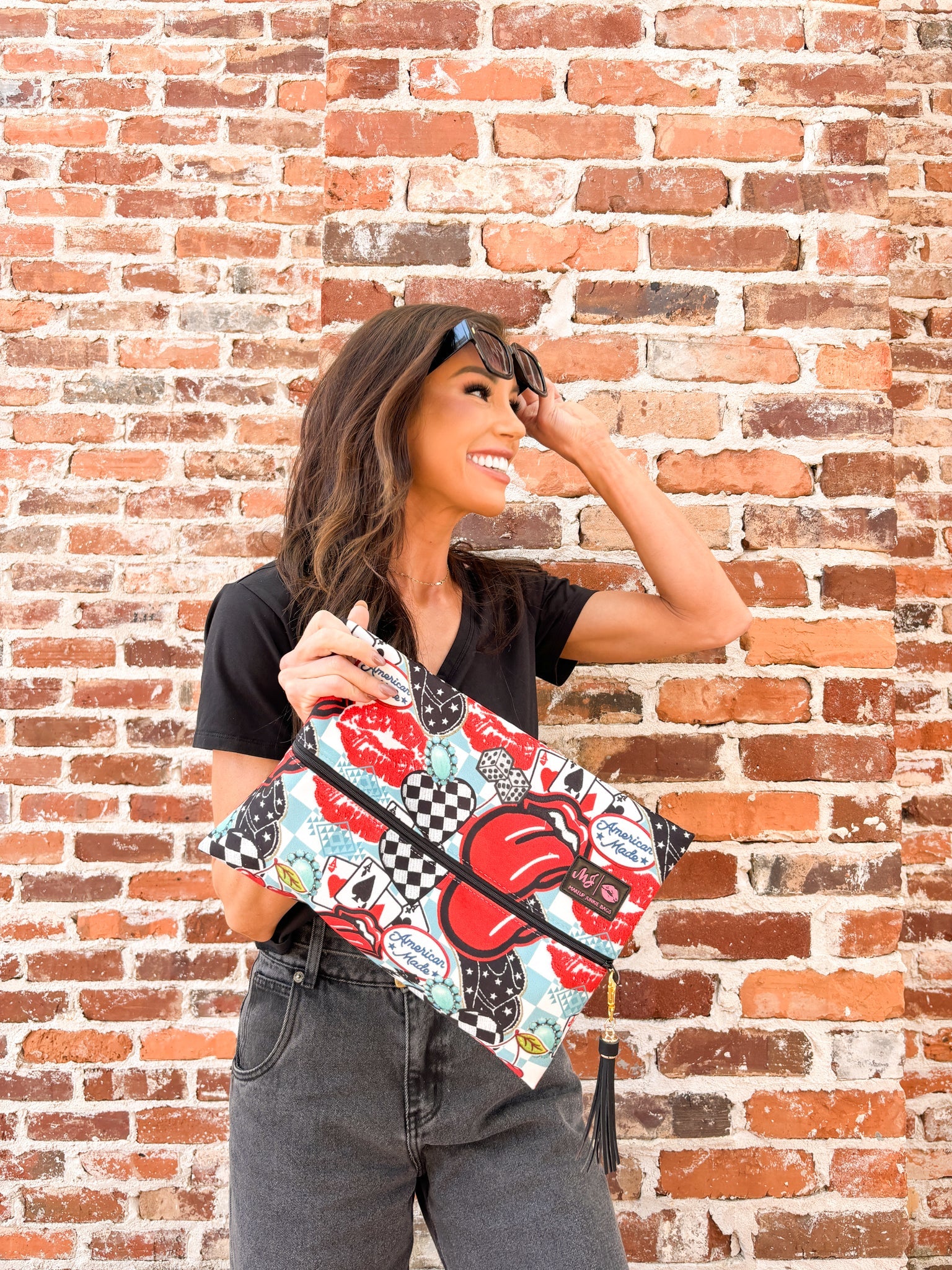 Woman holding a colorful patterned bag against a brick wall