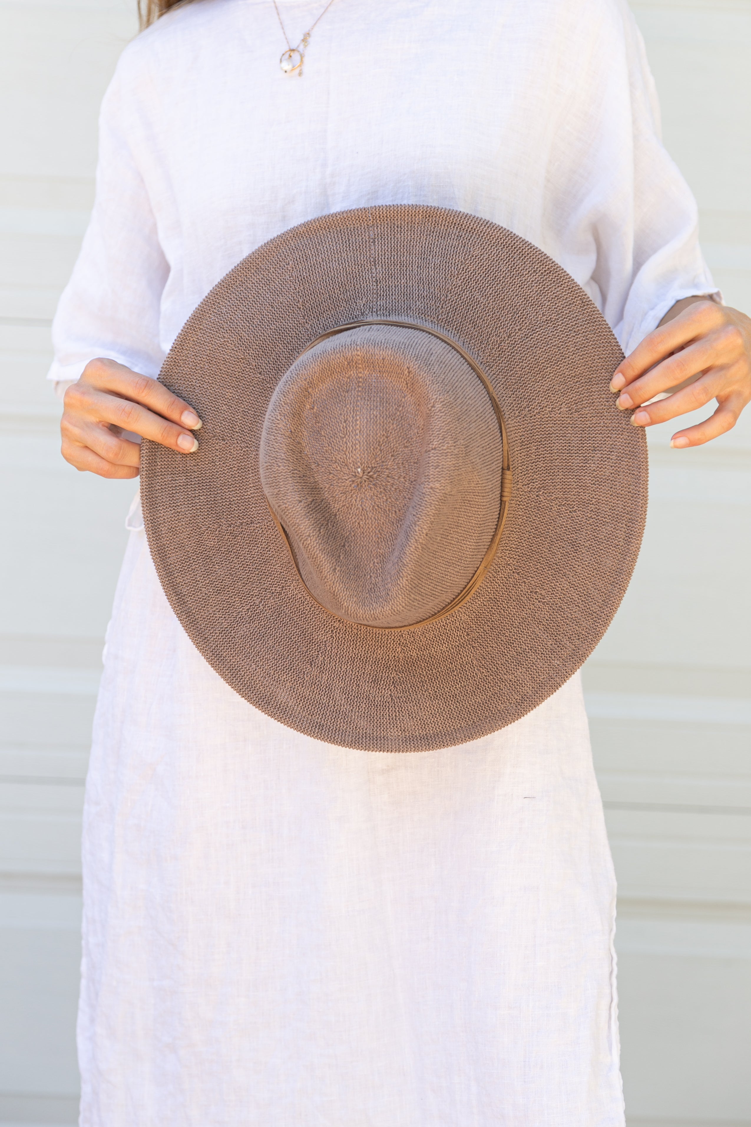 Person holding a brown hat against a white background