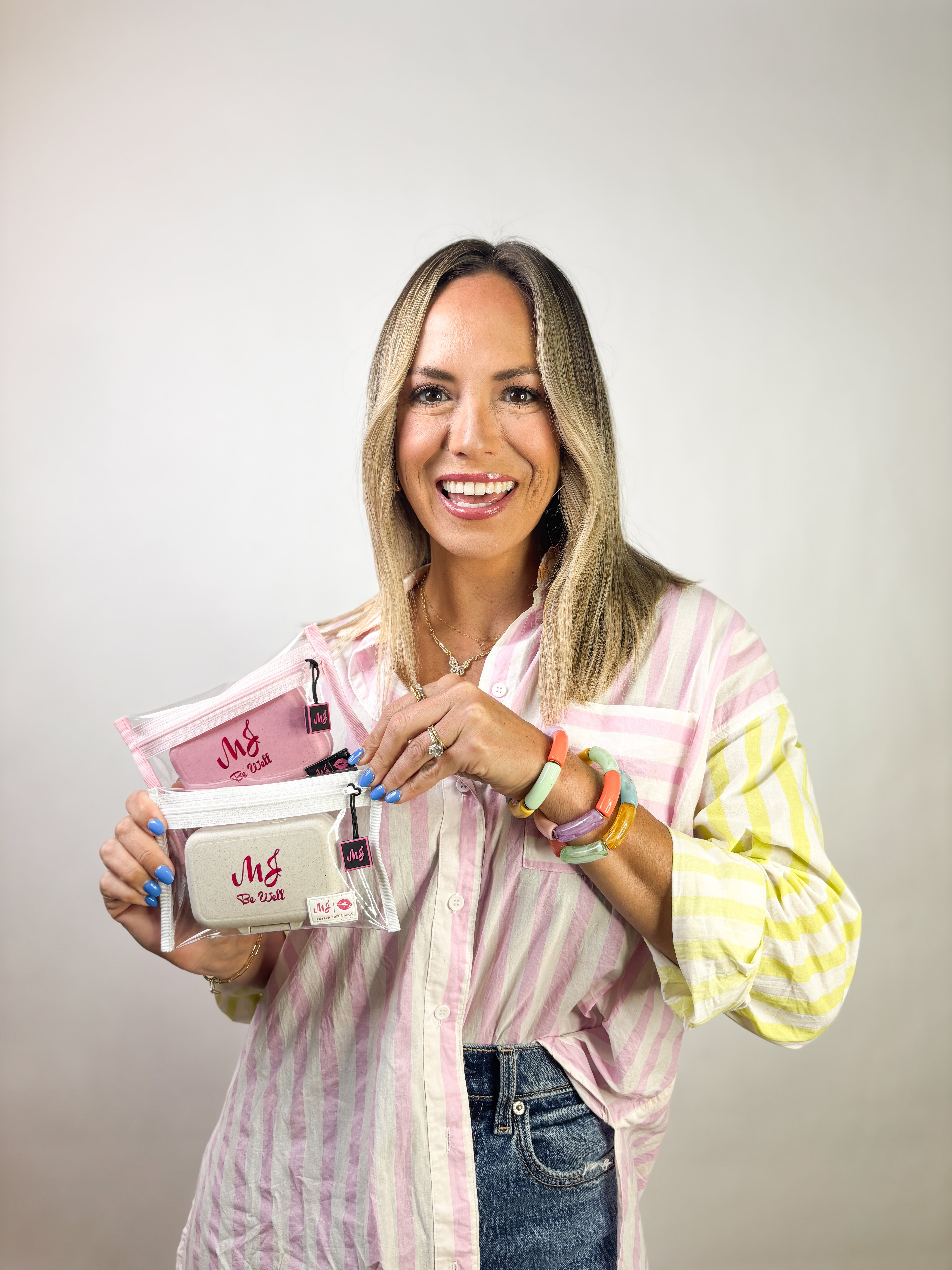 Woman holding a pink and white product packaging against a plain background