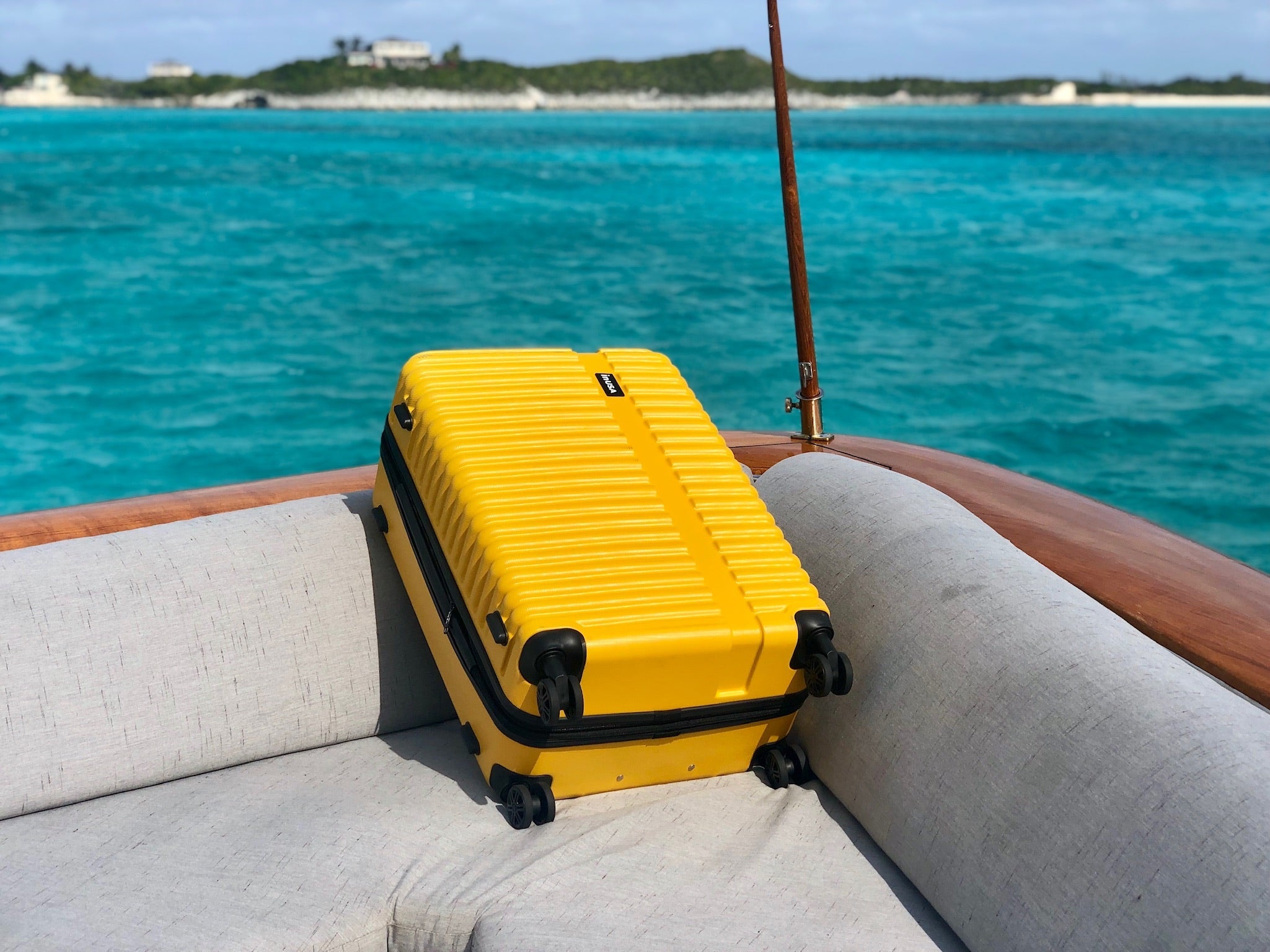Yellow suitcase on a boat with turquoise water and sky in the background