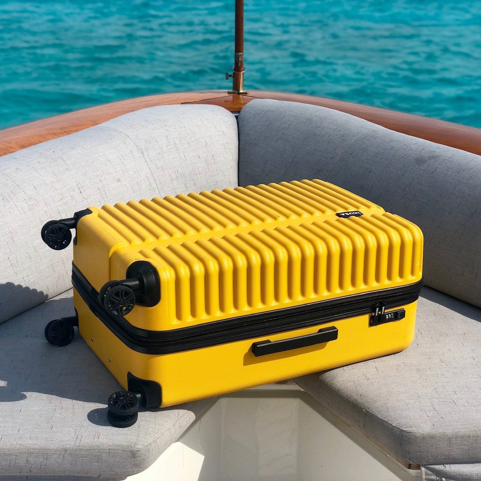 Yellow suitcase on a boat with blue water in the background