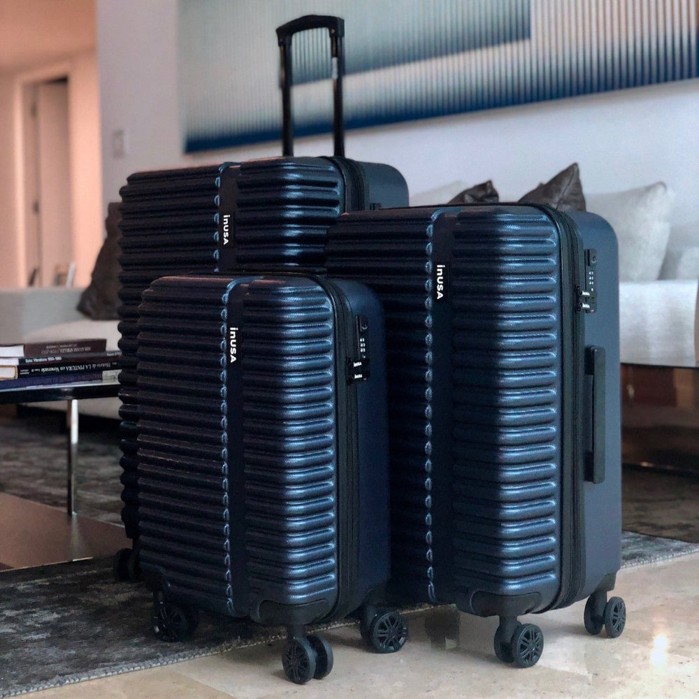 Set of black suitcases with 'InUSA' branding in a living room setting.