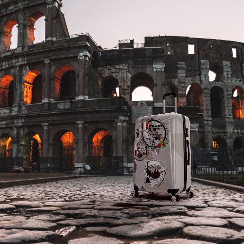 Suitcase with stickers in front of the Colosseum at dusk
