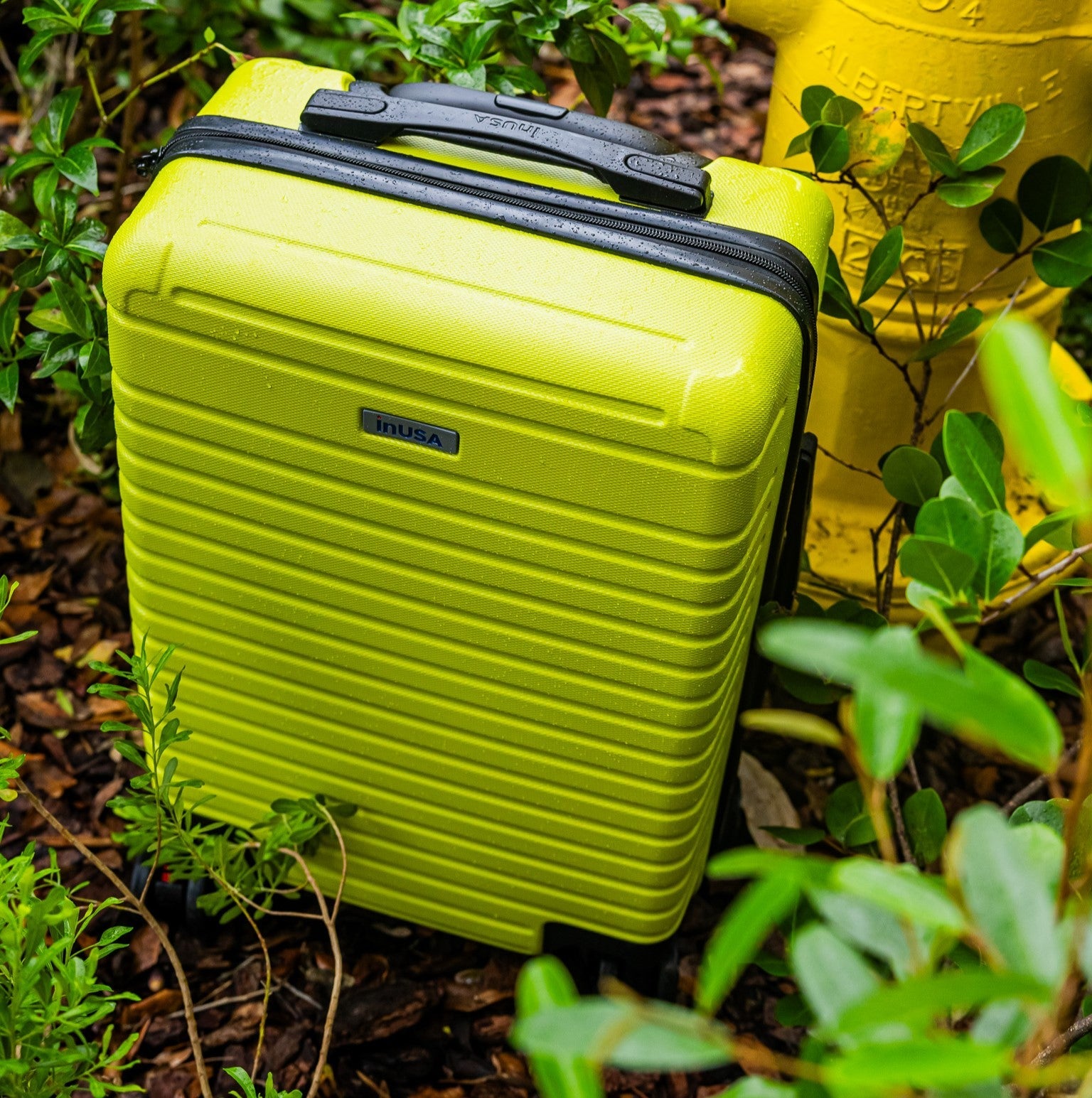 Green suitcase with black handle and trim on a natural background