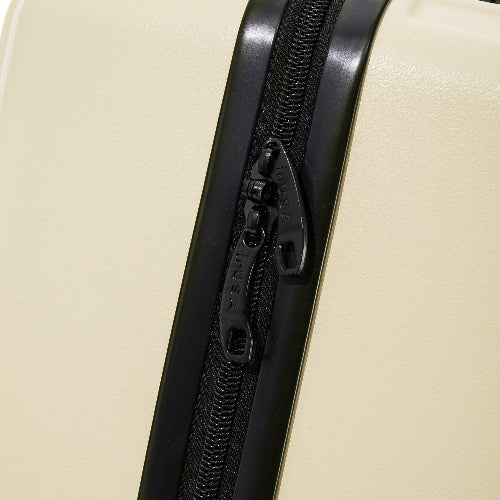 Close-up of a black zipper on a beige suitcase