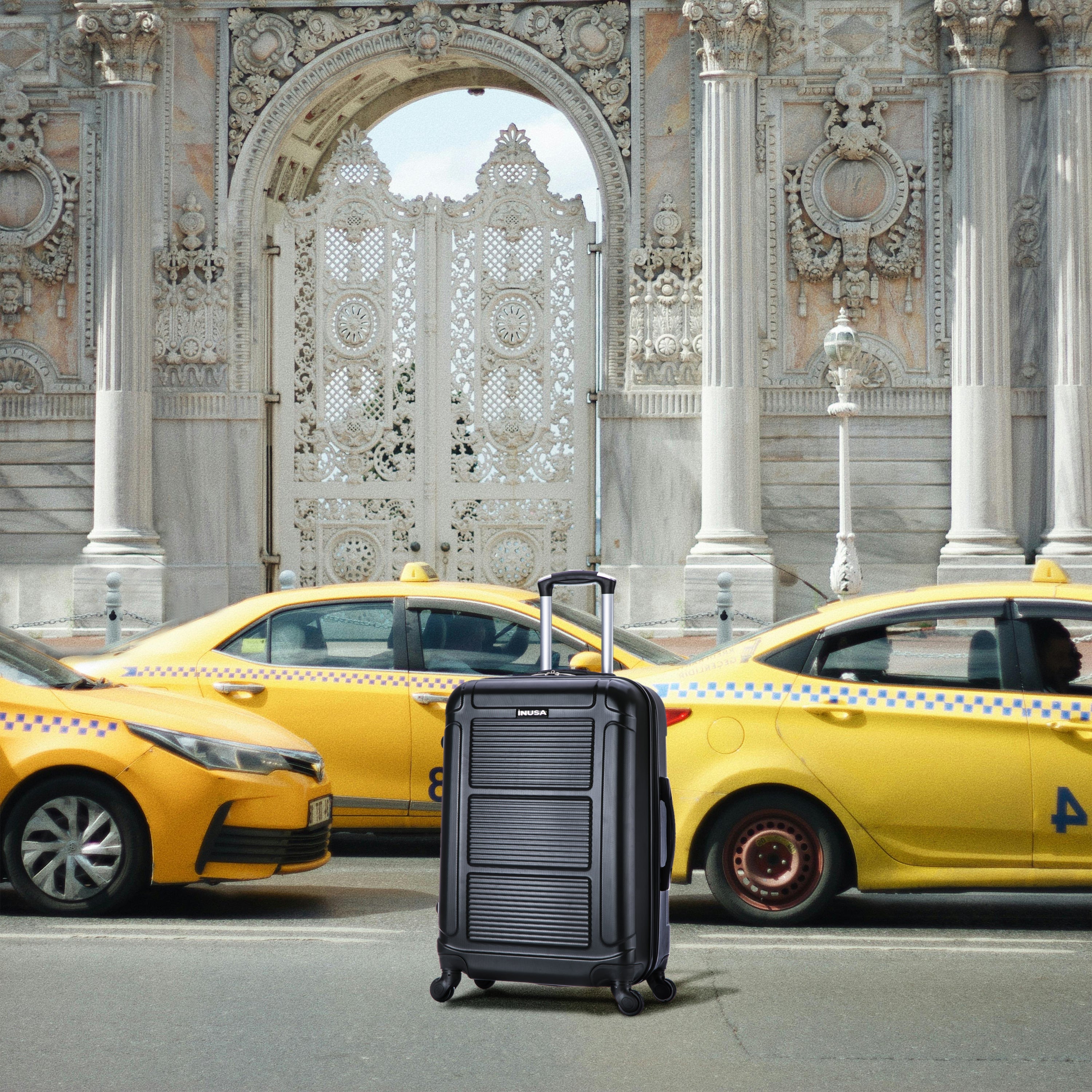 Black suitcase in front of yellow taxis with an ornate building in the background