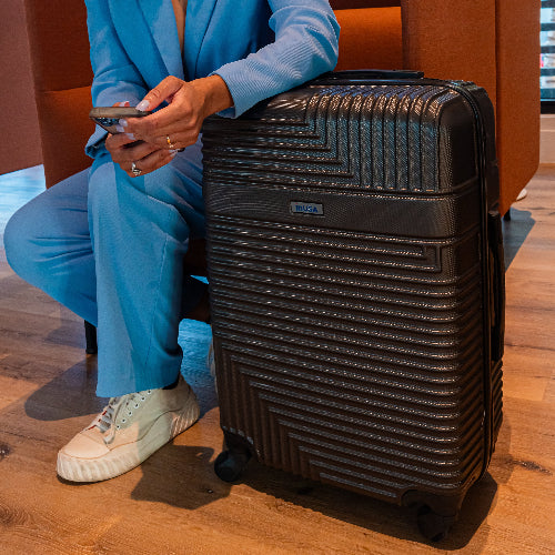 Person in blue outfit with black suitcase on wooden floor
