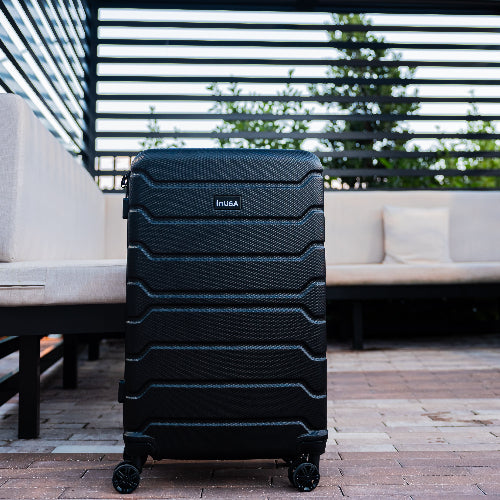 Black suitcase with 'INUSA' branding on a patio background