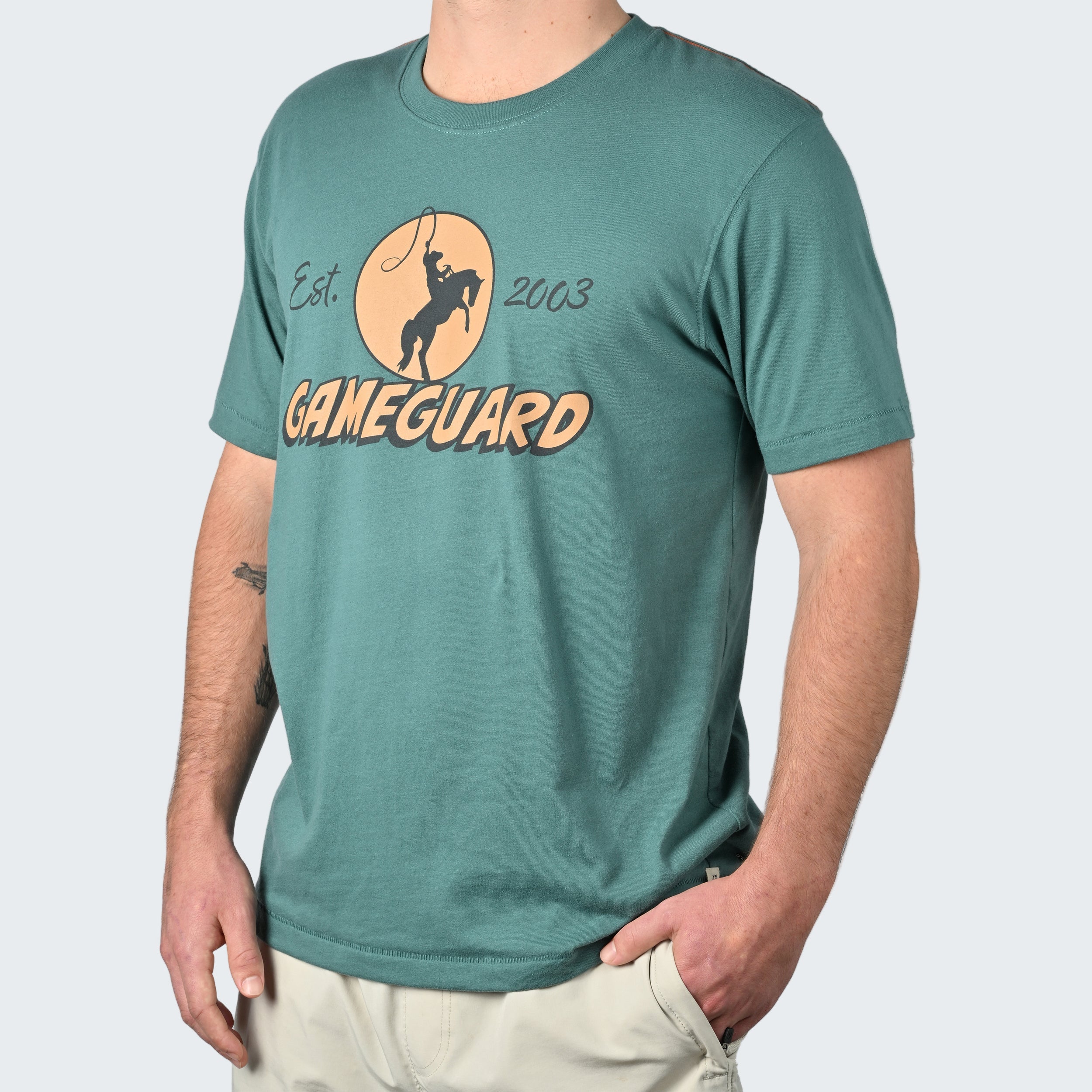 Person wearing a teal t-shirt with 'GameGuard' logo on a white background