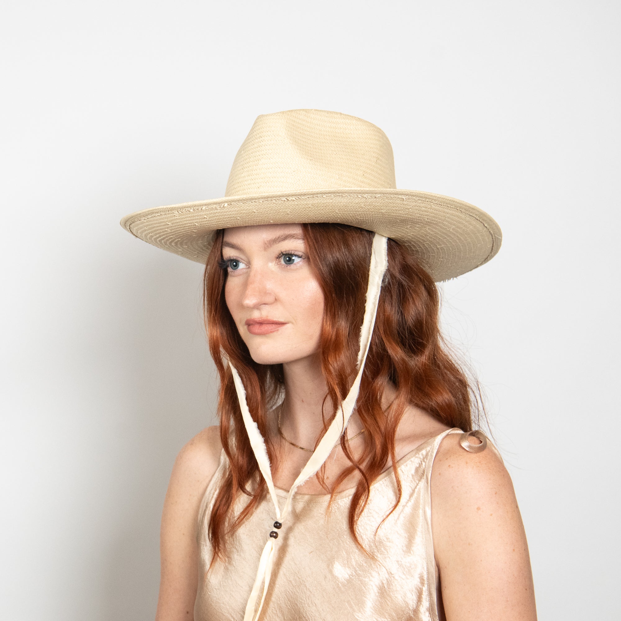 Woman wearing a beige wide-brimmed hat with a white background
