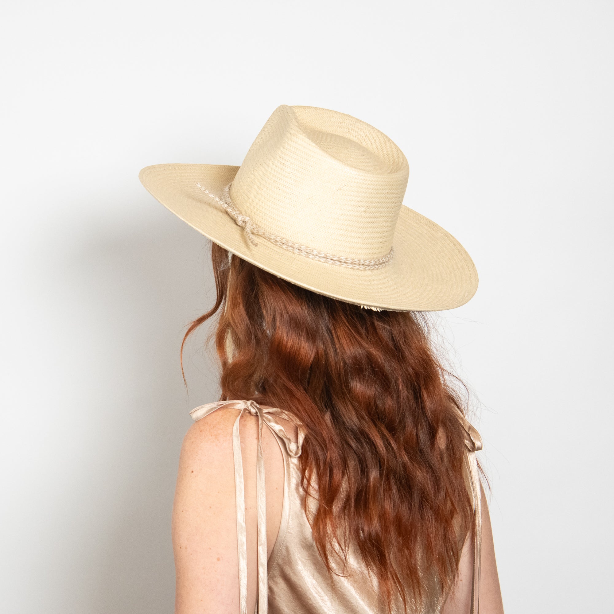 Person wearing a beige straw hat on a plain background