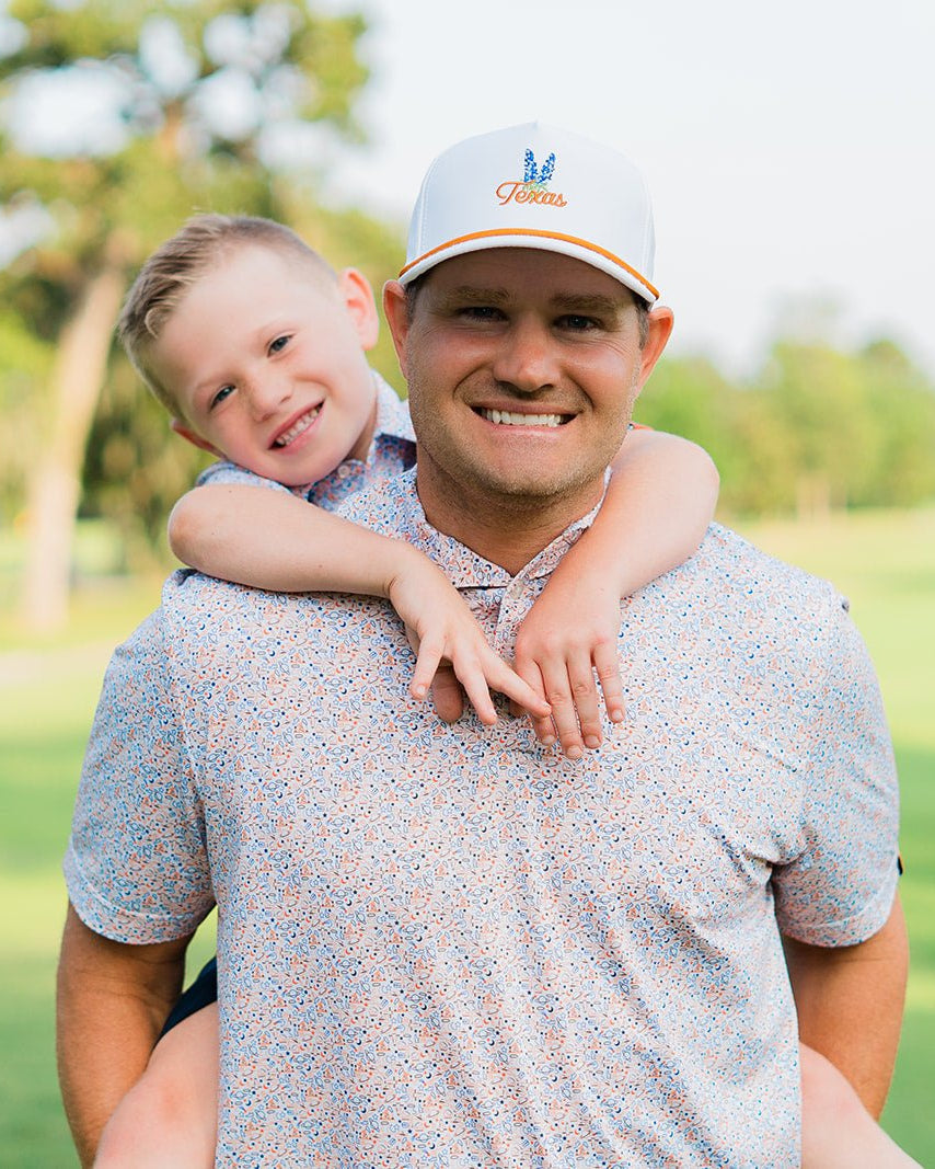 Man with a child on his shoulders, both smiling outdoors