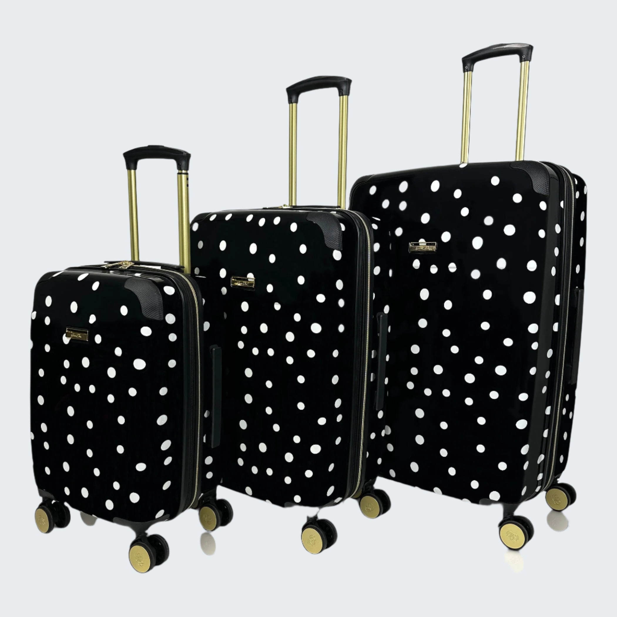 Set of three black suitcases with white polka dots on a white background