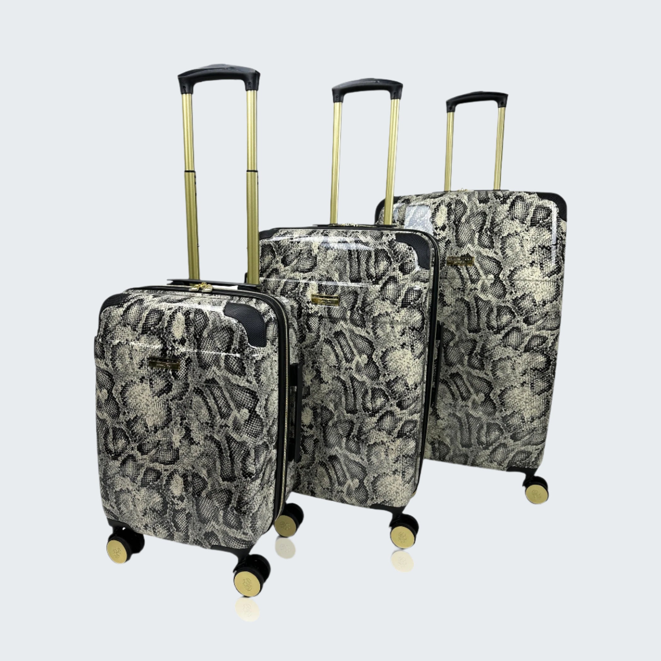 Set of three patterned suitcases with gold handles and wheels on a white background