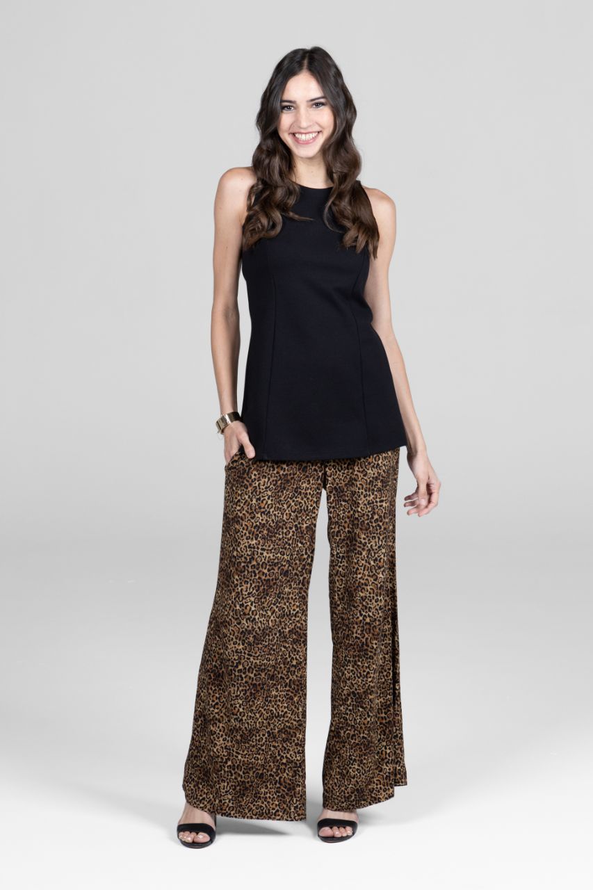 Woman wearing a black sleeveless top and patterned pants on a white background
