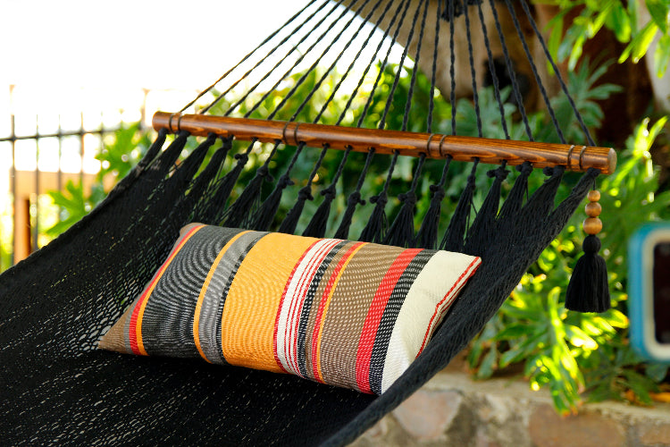 Black hammock with a striped pillow against a green outdoor background